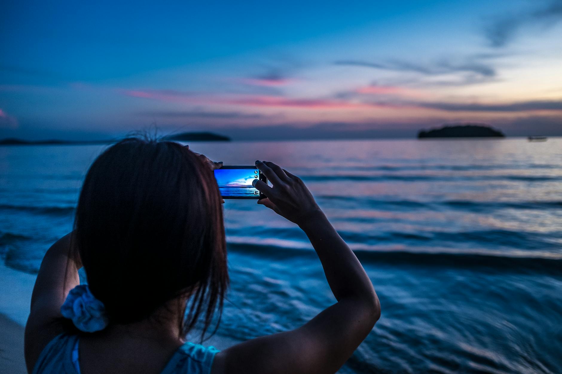 A person captures the stunning sunset over the ocean in Sihanoukville with a smartphone.