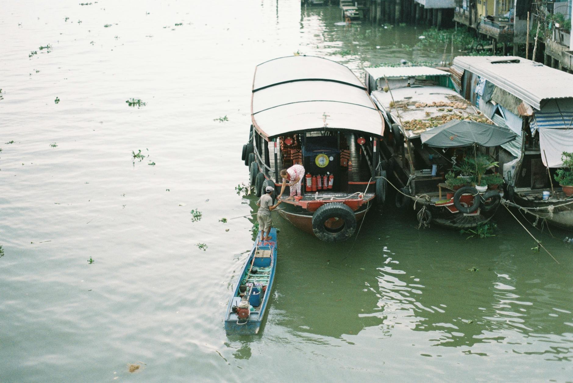 Tranquil village life depicted with boats on a calm river, capturing rural serenity.