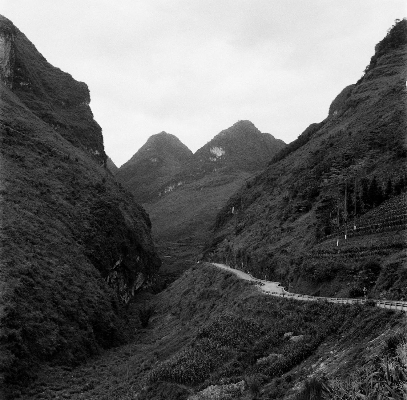 Black and white image of a winding road in Ha Giang, Vietnam's mountainous landscape.