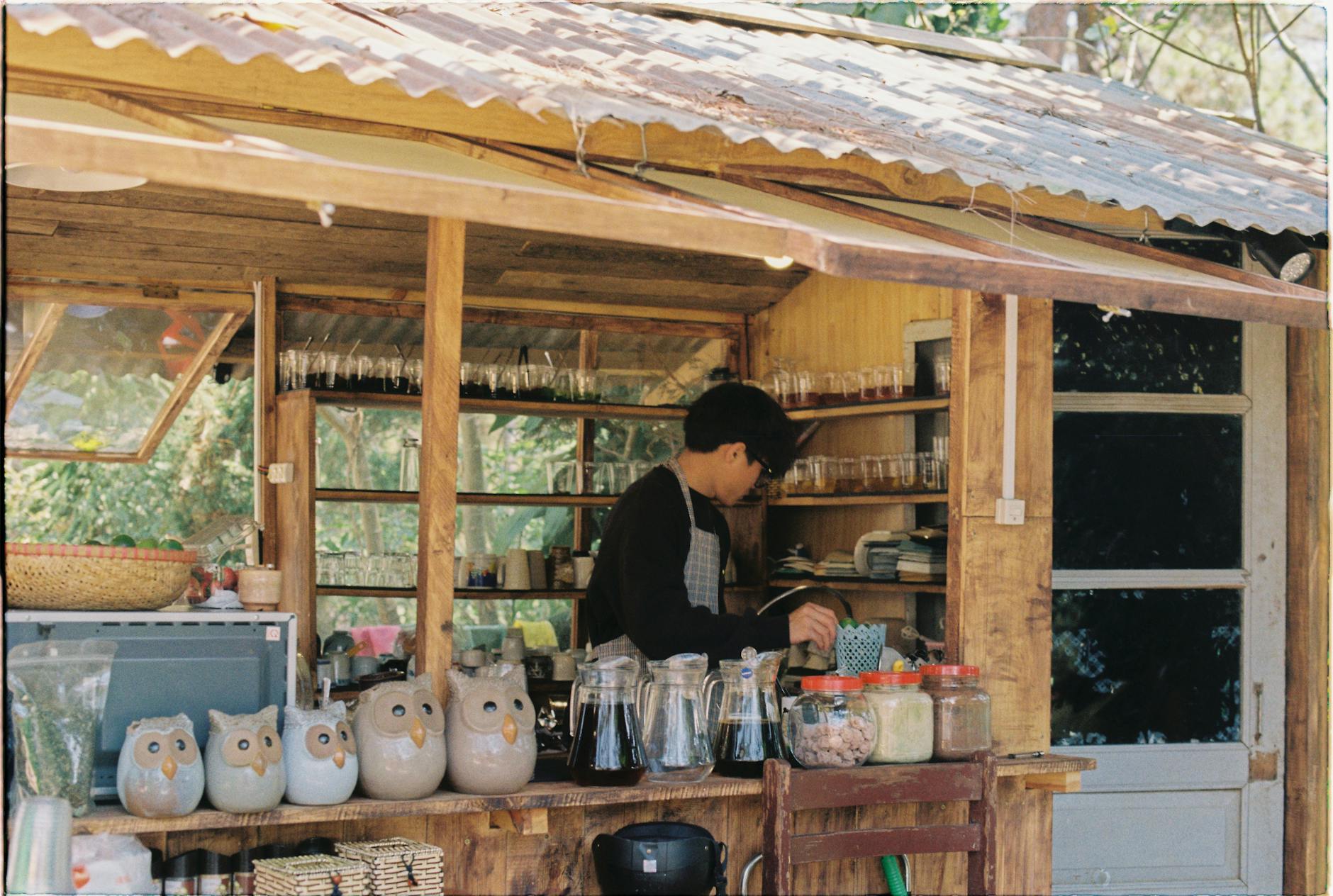 A rustic outdoor cafe in Vietnam featuring unique owl mugs and a vendor preparing drinks.