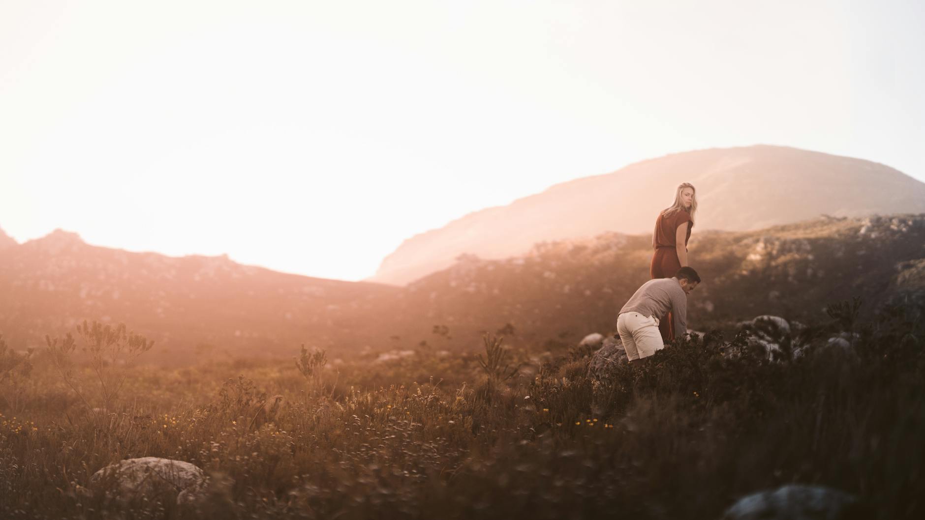 A couple stands in a misty mountain field at sunrise, embracing adventure.