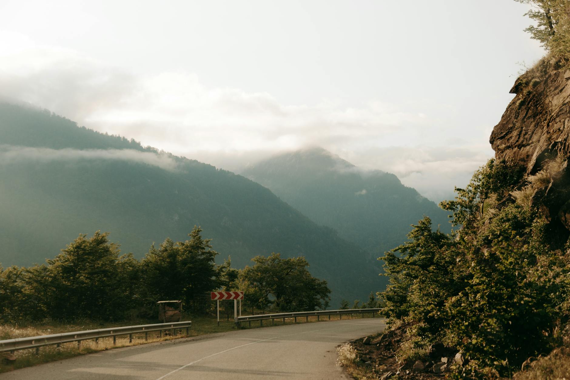 Scenic foggy mountain road with lush greenery and distant misty peaks. Ideal for travel themes.