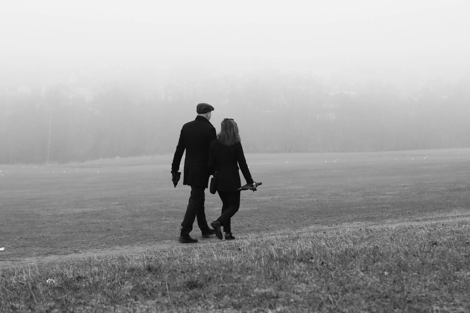 A couple enjoys a romantic walk on a foggy day in Jönköping's serene landscape, Sweden.