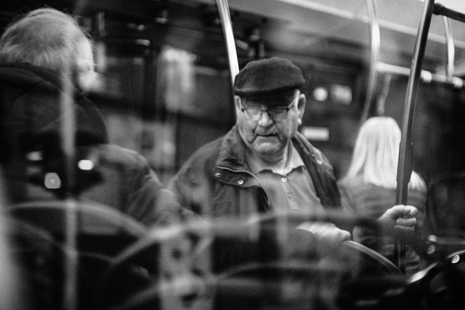 Black and white photo capturing an older man on a bus, reflecting public transit life.