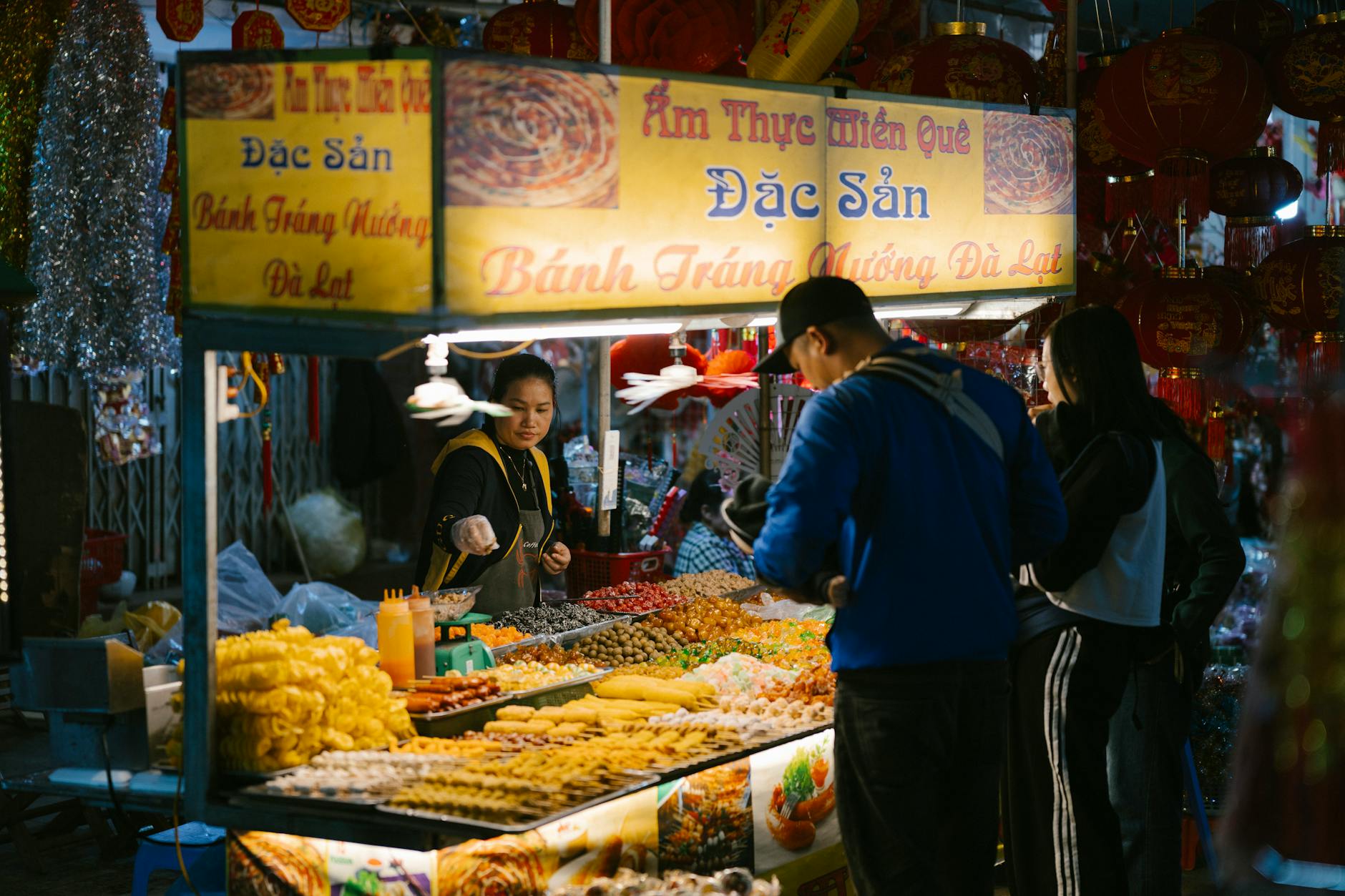 Vibrant night market scene with a Vietnamese food stall offering diverse local snacks and delicacies.