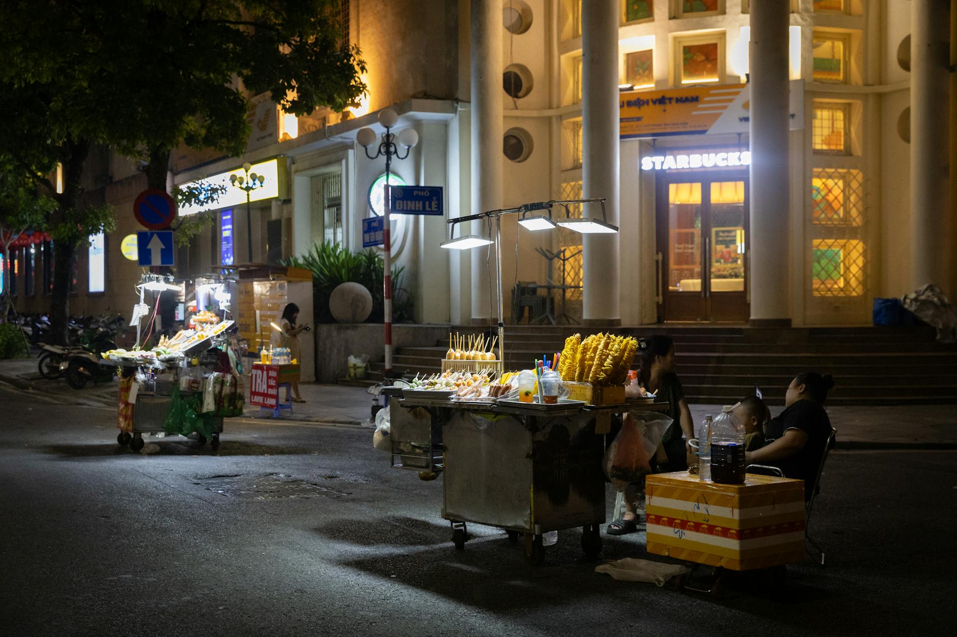 Lively street food scene in Hanoi's old town at night with vibrant vendor stalls.