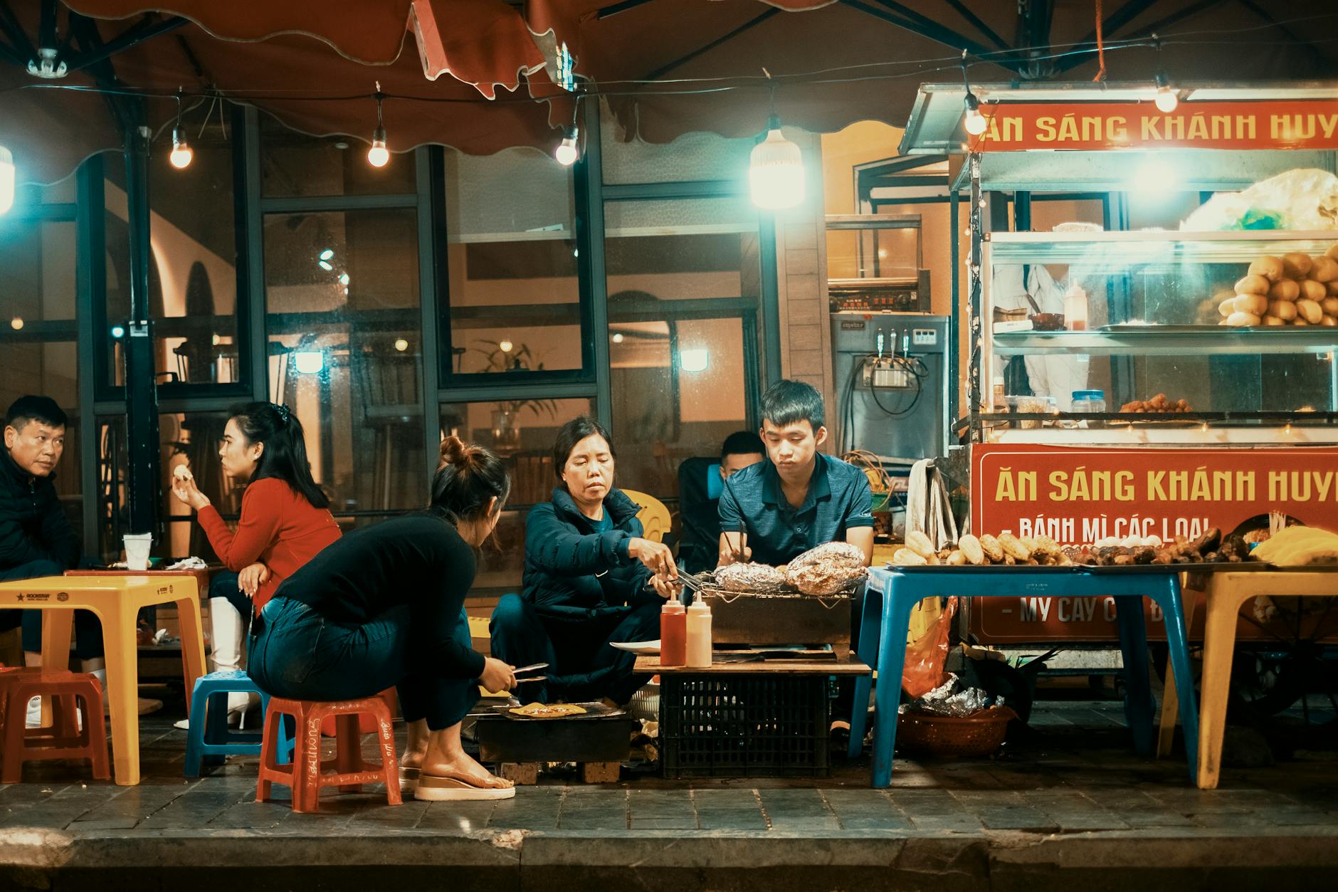Group enjoying street food at night in a vibrant Vietnamese setting.
