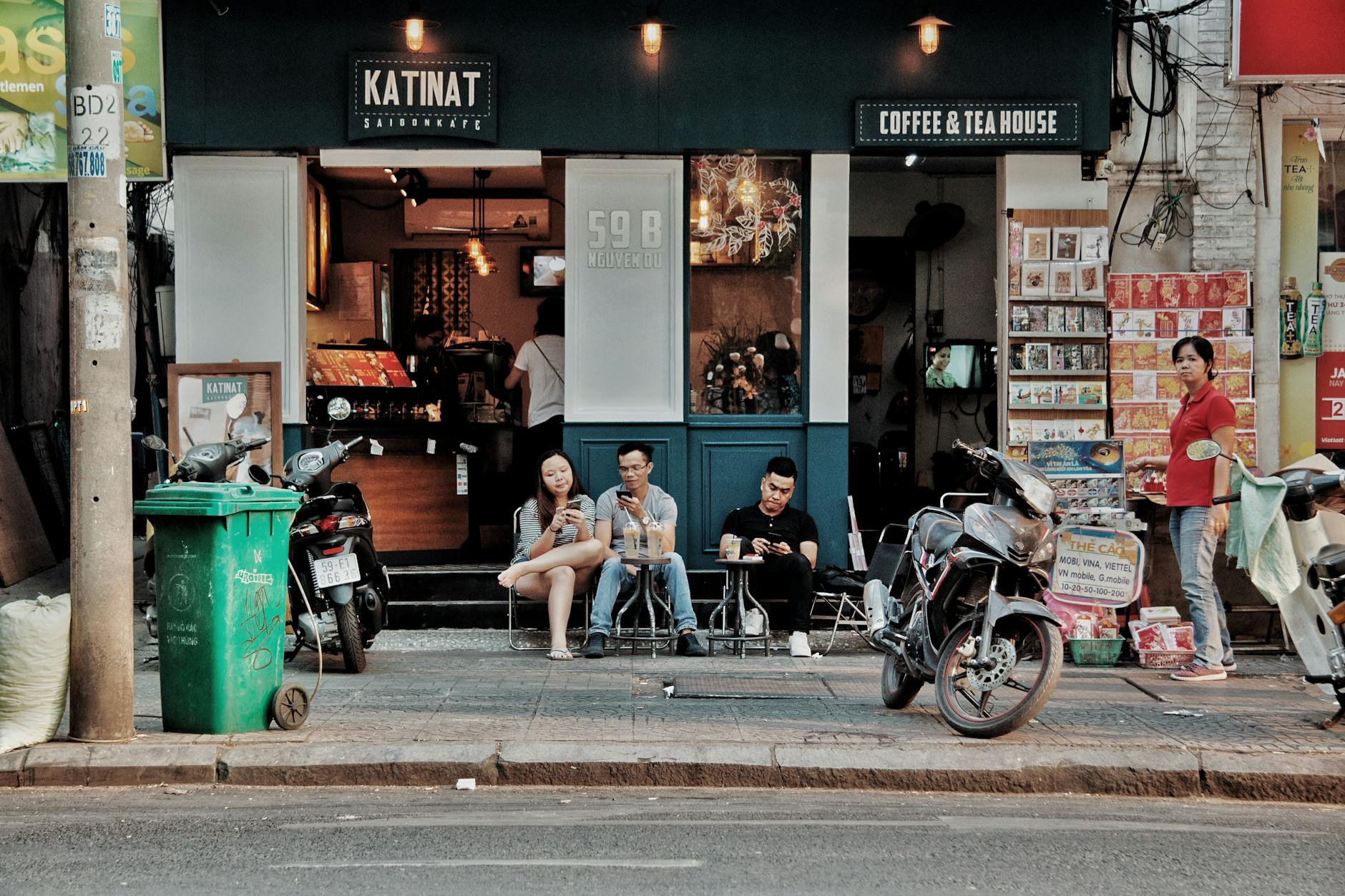 People sitting outside a coffee shop in an urban setting, enjoying drinks and conversation.