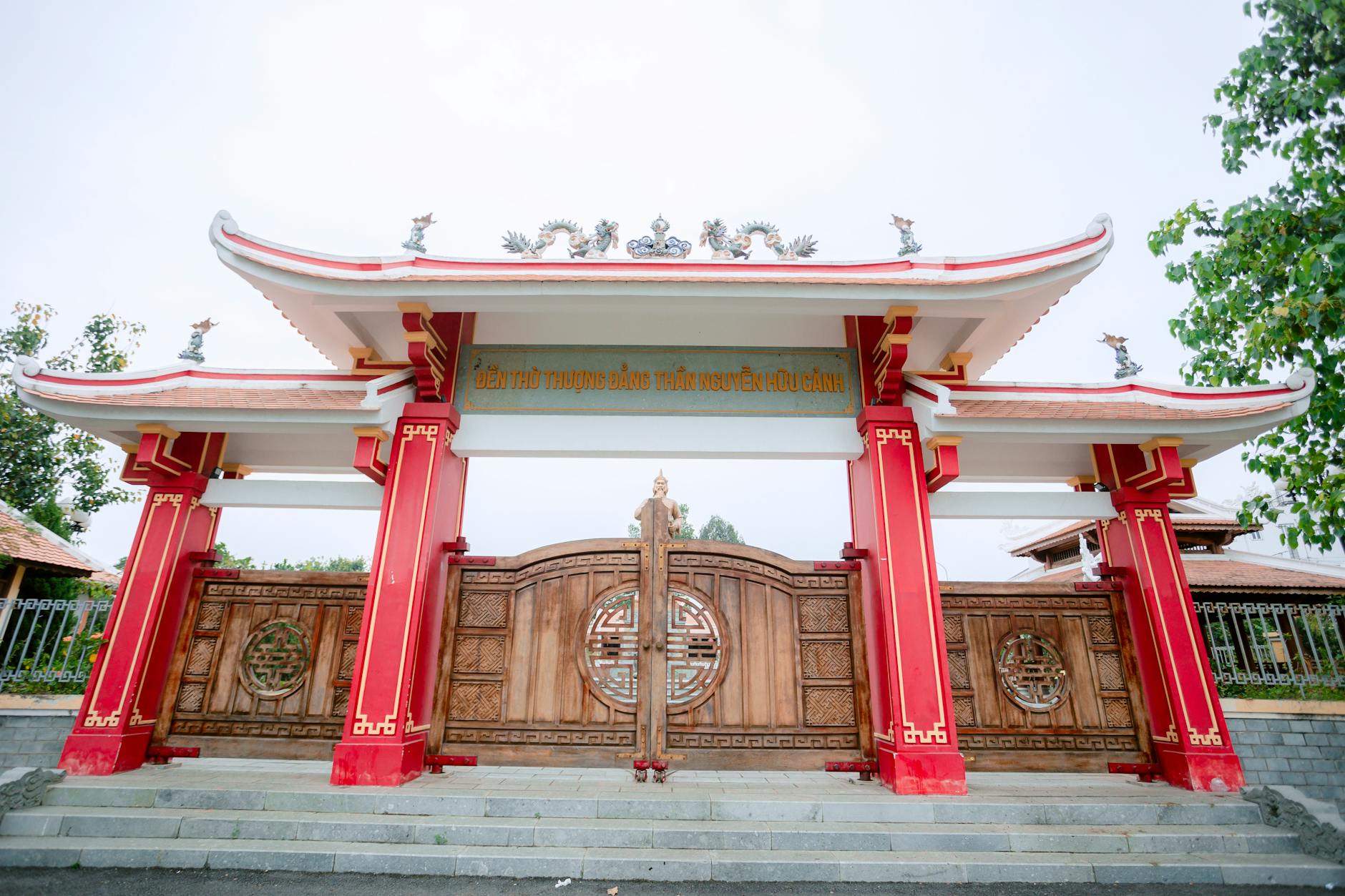 Elegant traditional Asian temple gate featuring red and wooden elements, captured in daylight.