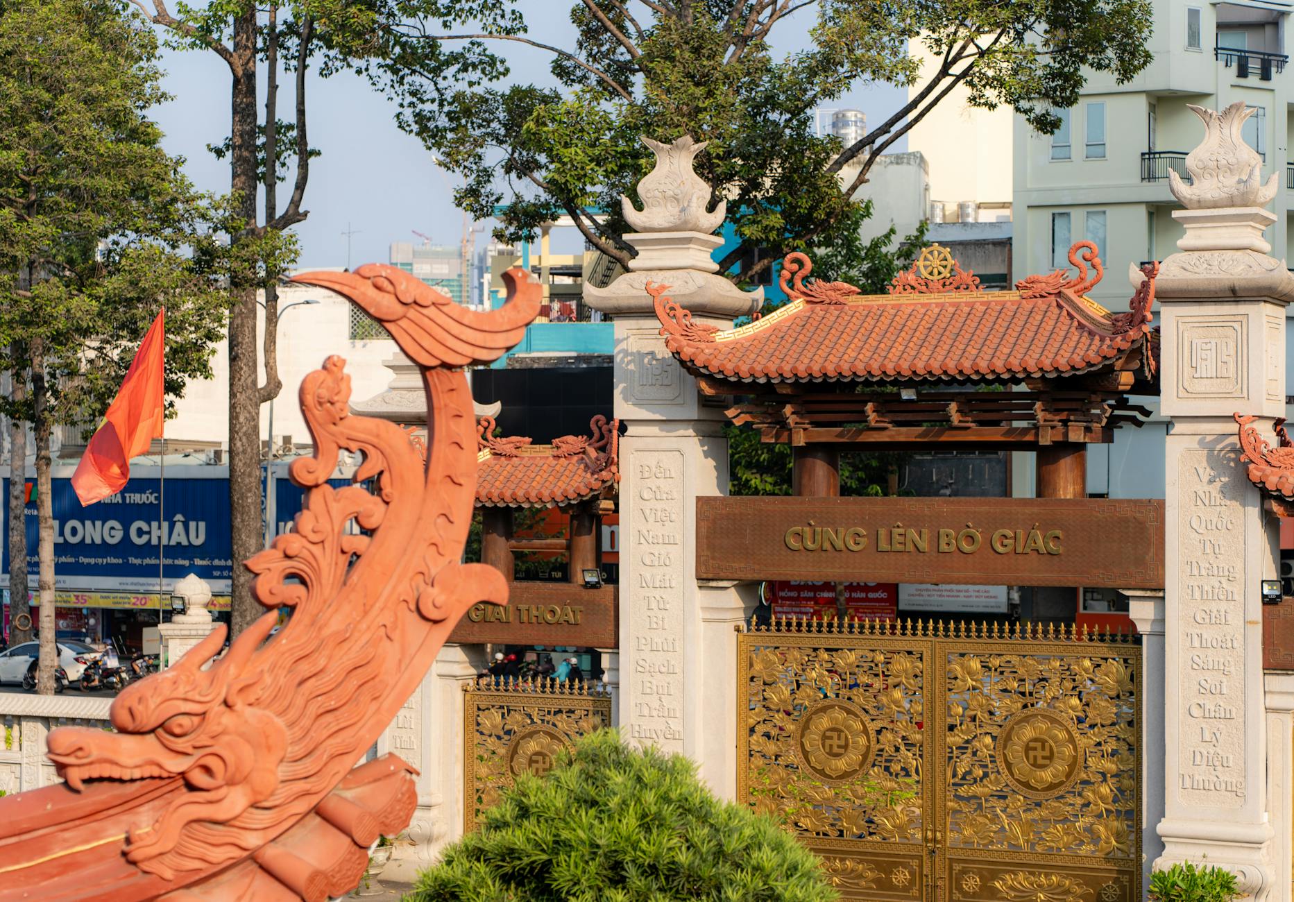 A traditional Vietnamese temple entrance with intricate designs and a dragon motif under bright sunlight.