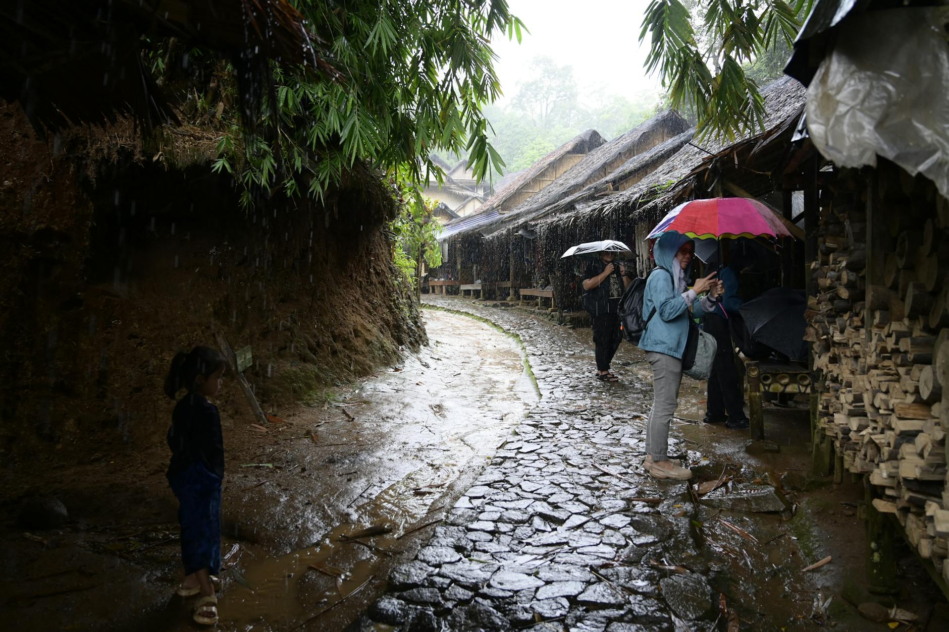 A rainy day at a traditional village in Banten, Indonesia, with people under colorful umbrellas.