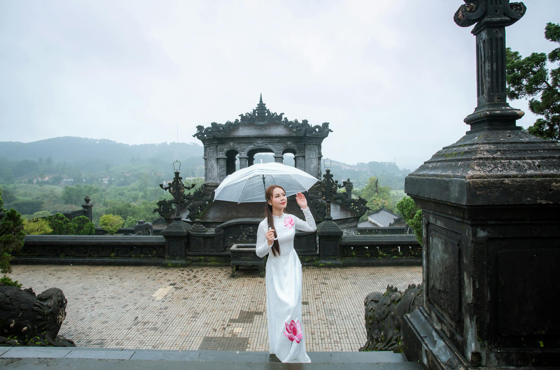 Woman in traditional dress with umbrella at a historical site in Vietnam.