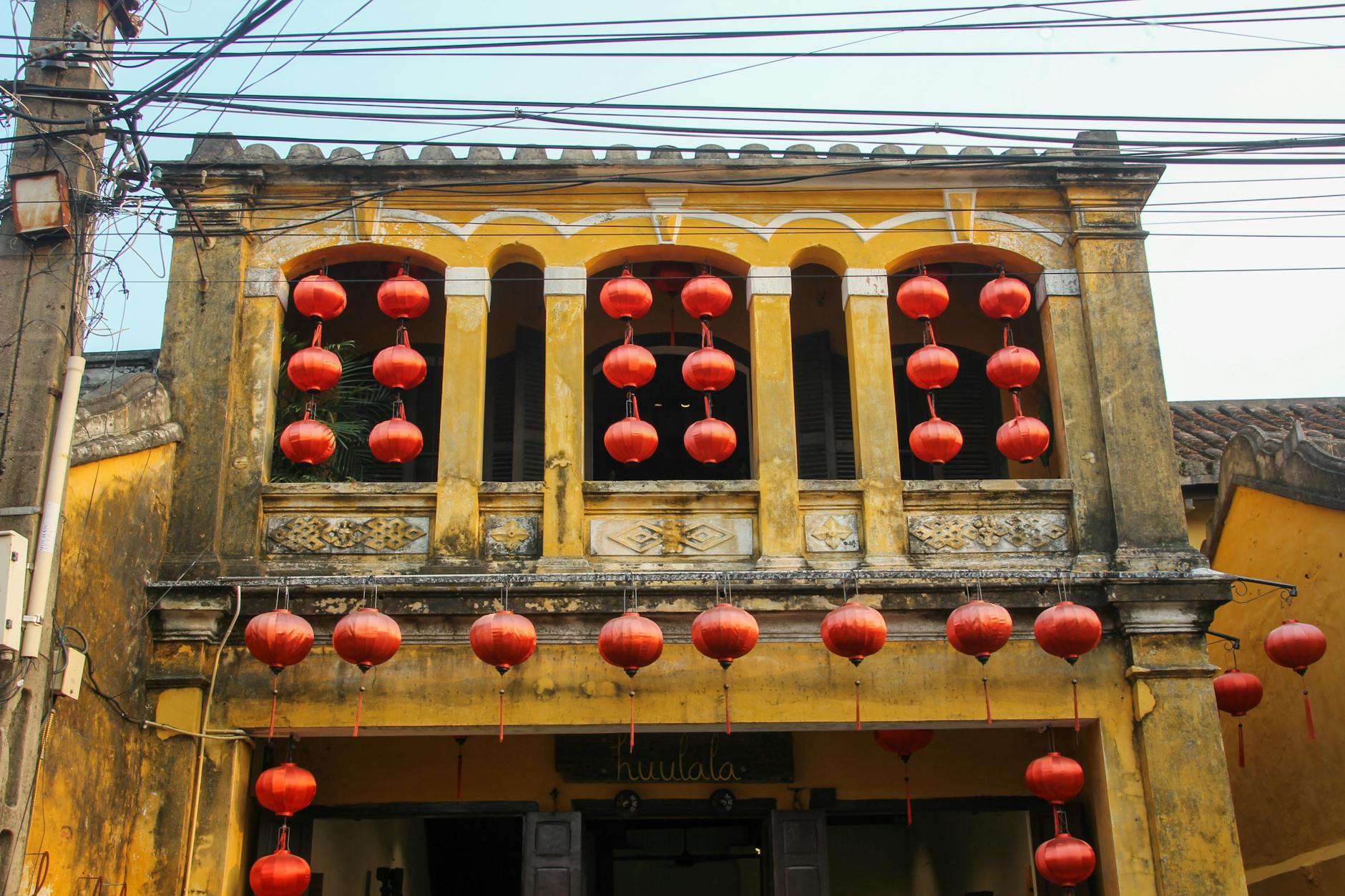 Capture of a vintage yellow building adorned with red lanterns in Hội An, Vietnam.