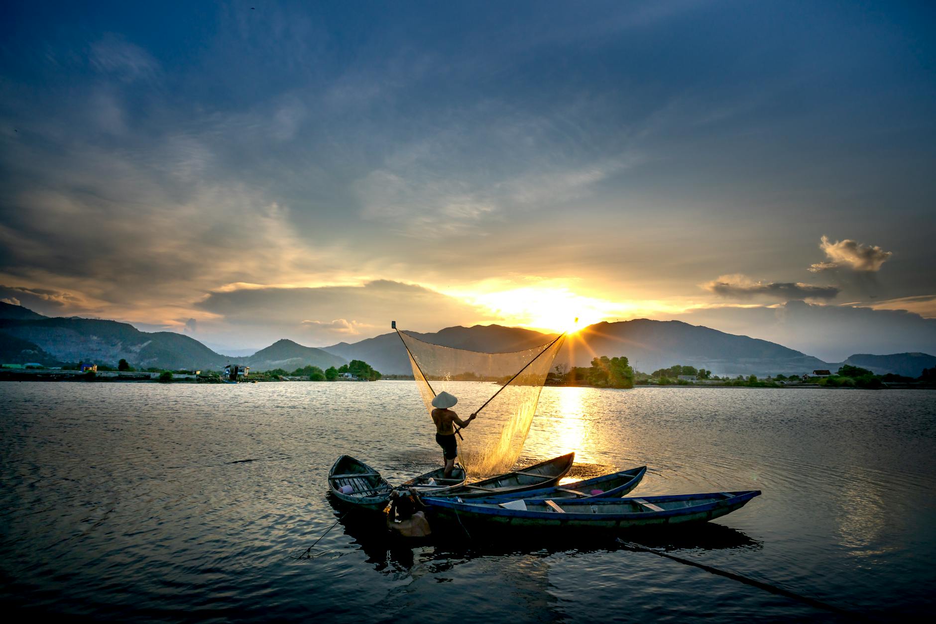 A serene view of a fisherman casting his net at sunrise in Nha Trang, Vietnam.
