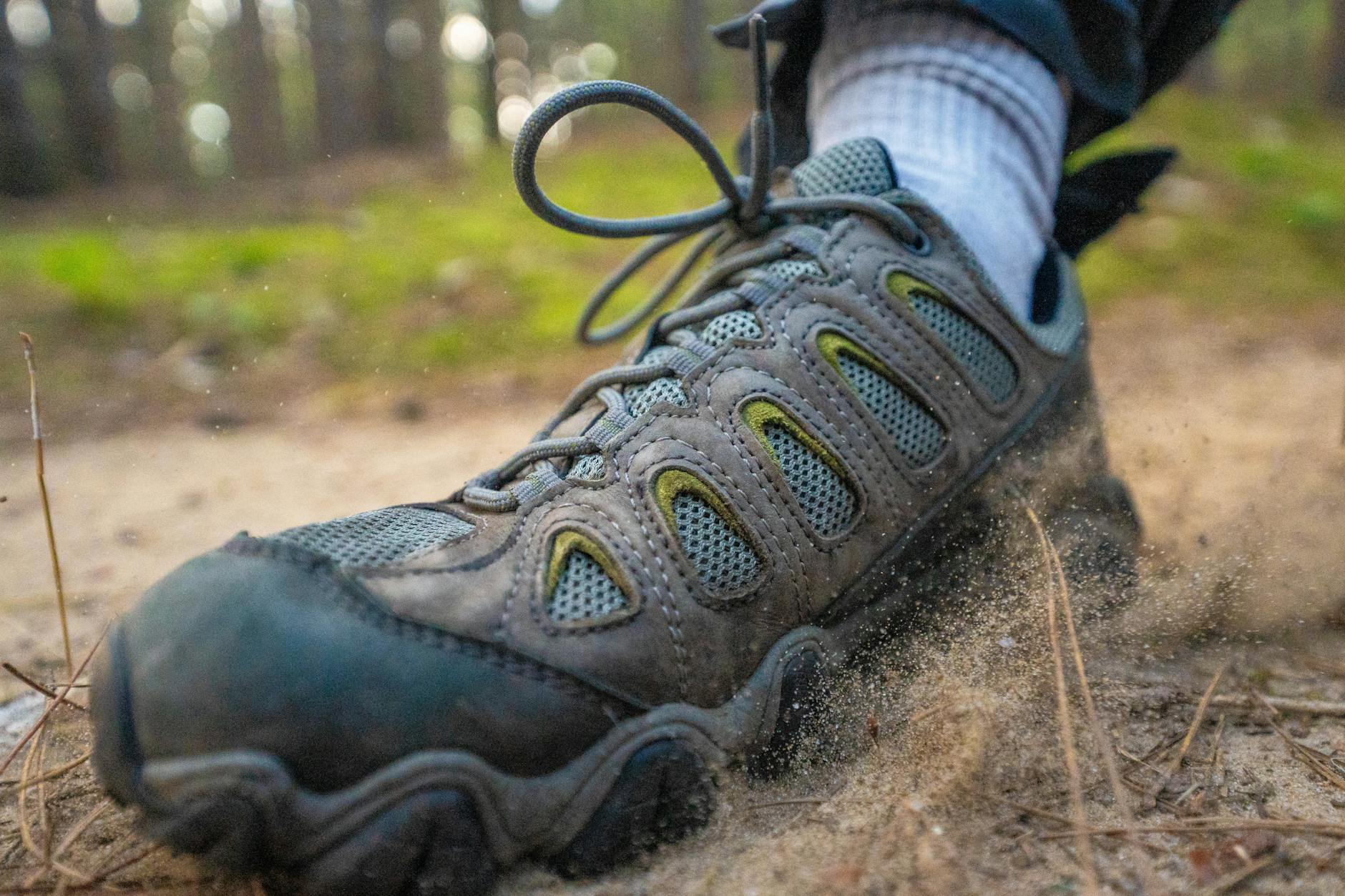 Close-up of a hiking boot kicking up sand on a forest trail, perfect for adventure themes.