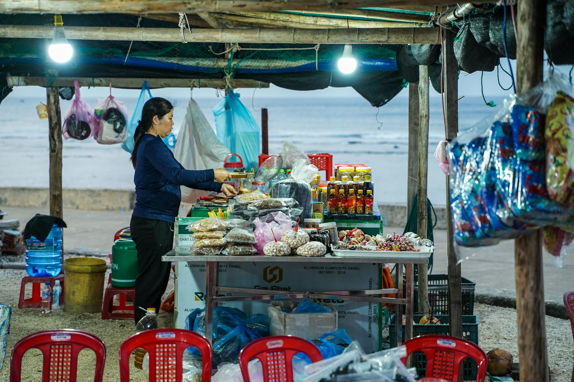 A local vendor woman sells goods at an outdoor coastal market stall in Ly Son.