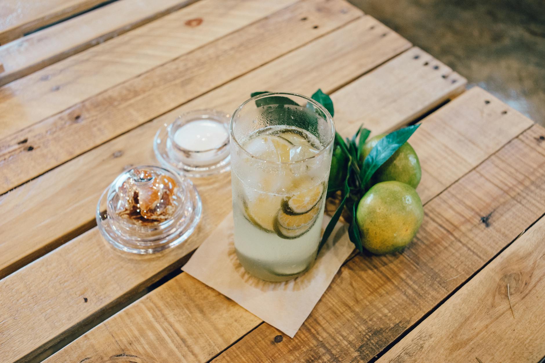 A refreshing iced lime drink served on a rustic wooden table with fresh limes. Perfect for summer vibes.