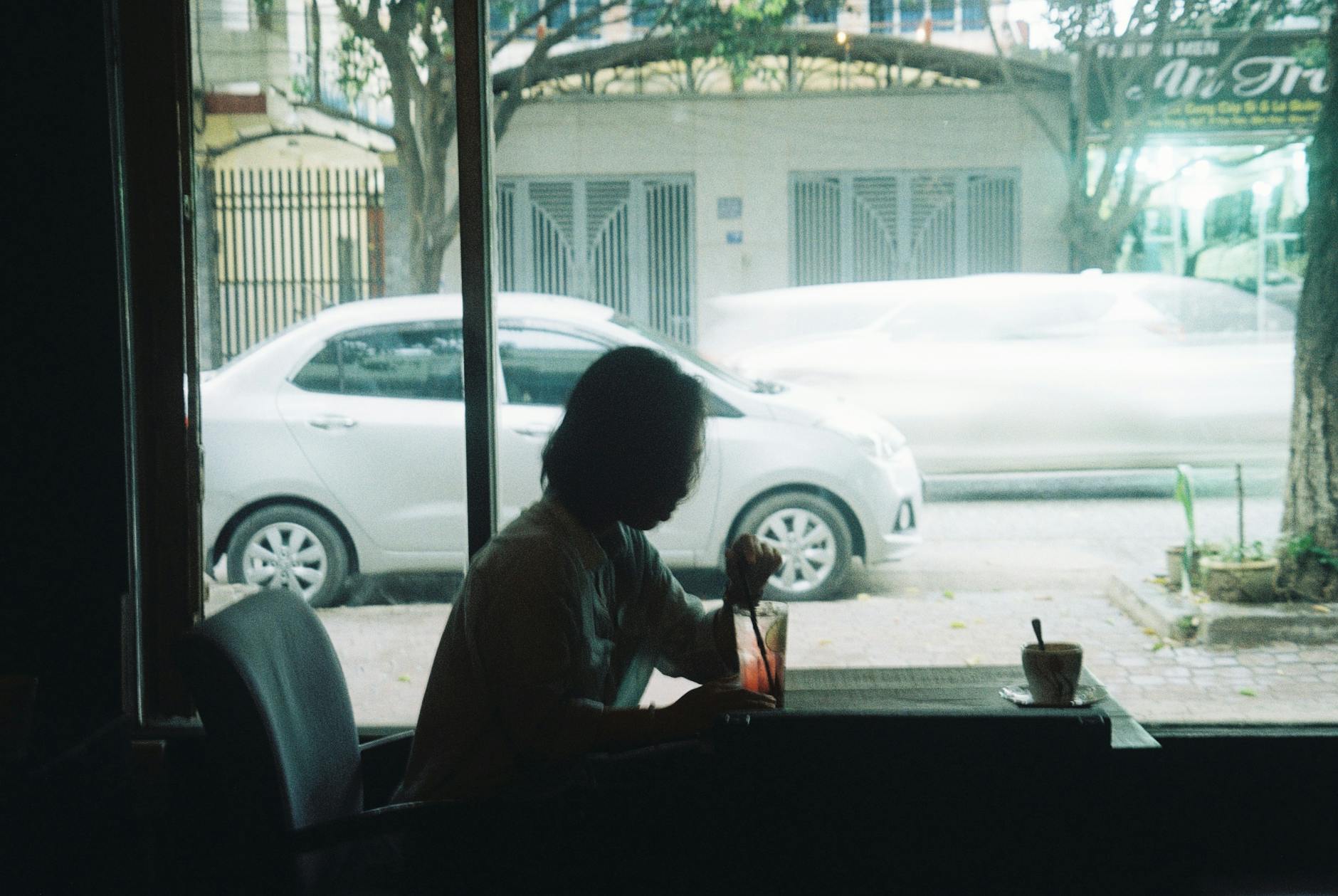 Silhouette of a person in a cafe with a street view in Ho Chi Minh City, Vietnam.