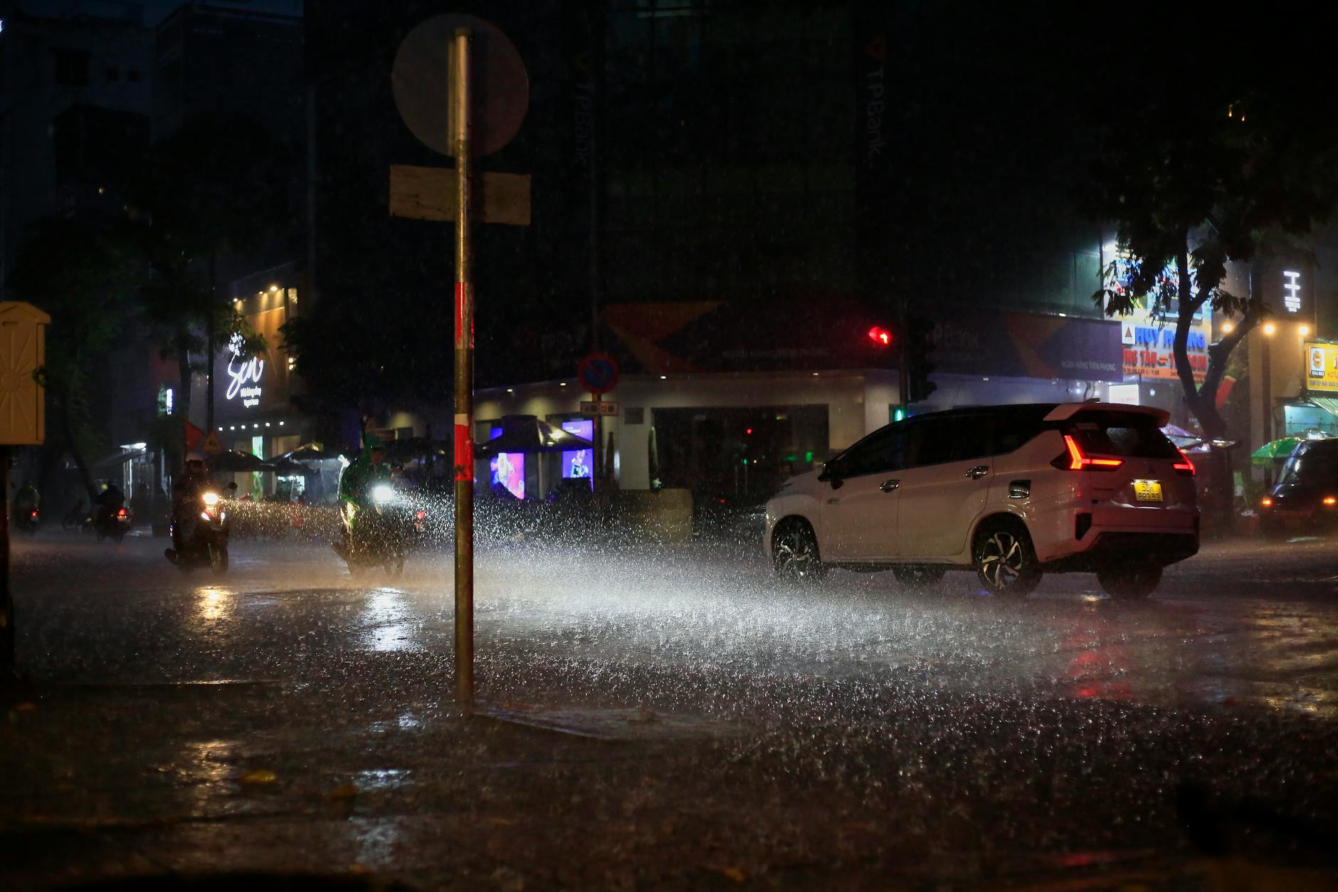 Nighttime rain pours down on a busy street in Ho Chi Minh City, Vietnam, capturing urban life.