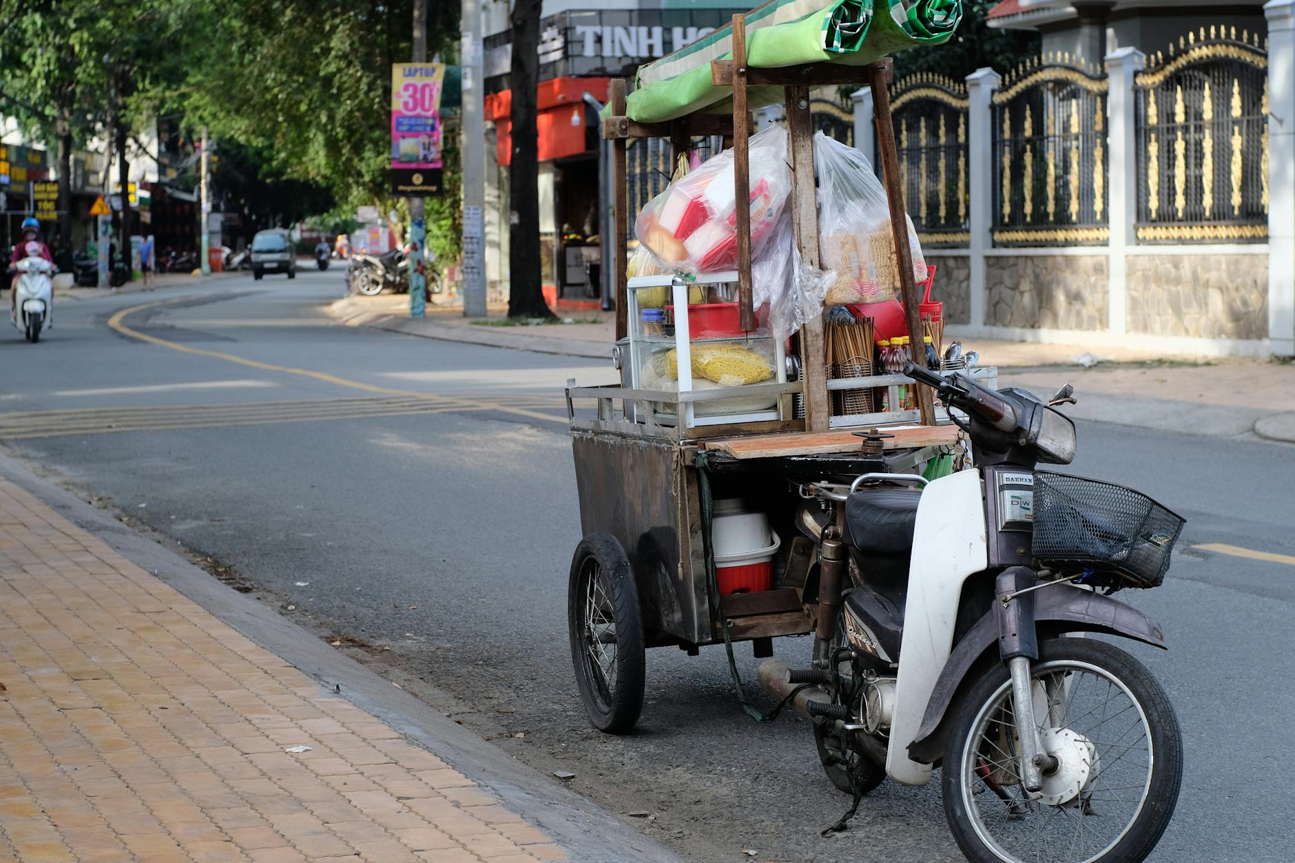 A street food cart attached to a motorbike on a quiet urban street, conveying local culture and daily life.