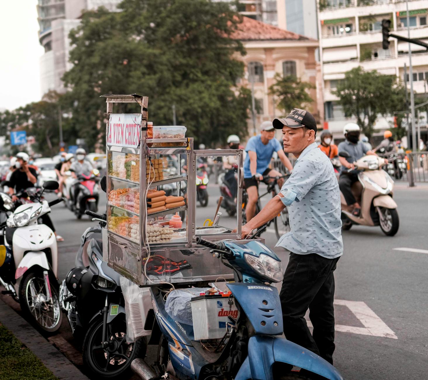 Street vendor with food cart amidst busy traffic, portraying urban hustle and local culture.