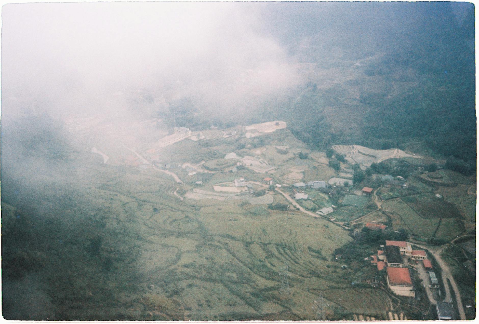A dreamy aerial view of rice terraces shrouded in mist in Sa Pa, Vietnam, capturing a serene rural landscape.