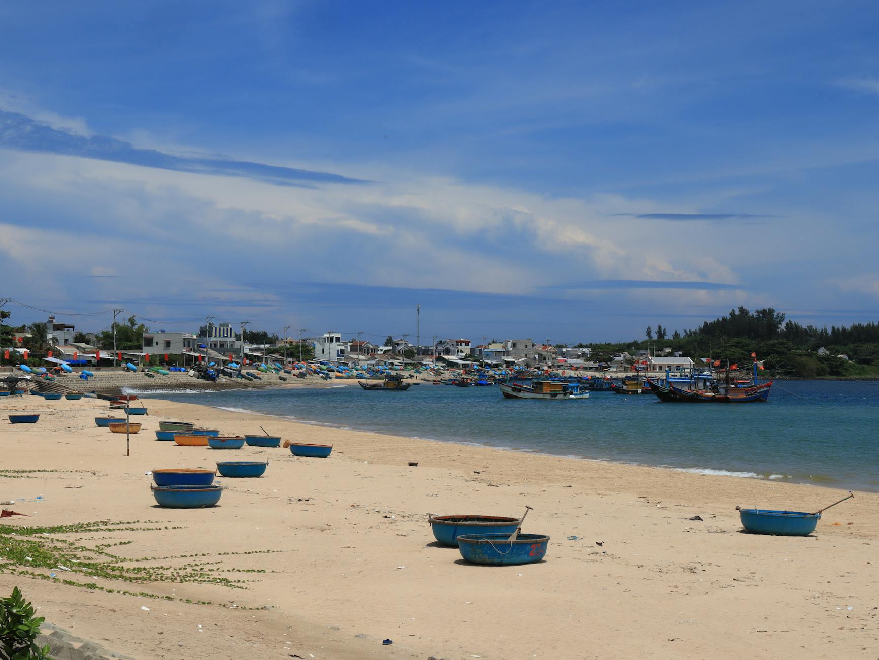 A tranquil village by the sea with fishing boats and sandy shores under a clear blue sky.