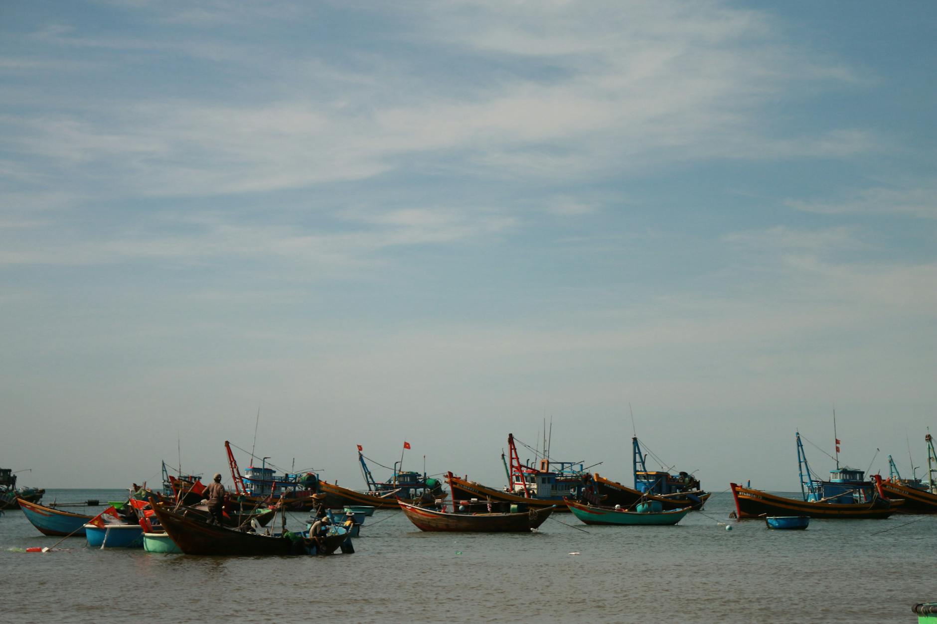 Traditional Vietnamese fishing boats anchored under clear blue skies on a calm day.