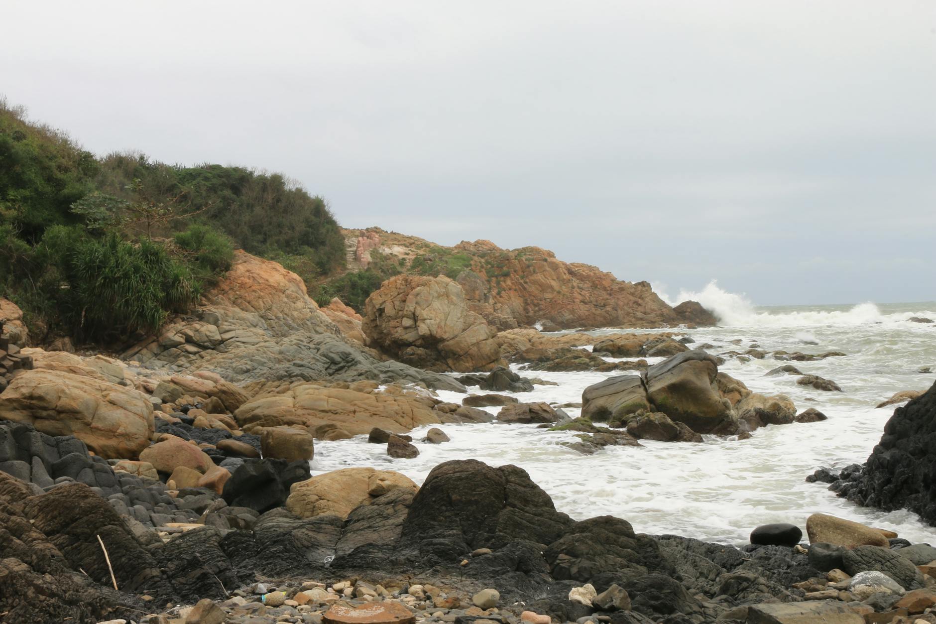 Dramatic rocky coastline in Vietnam with waves crashing onto the shore.