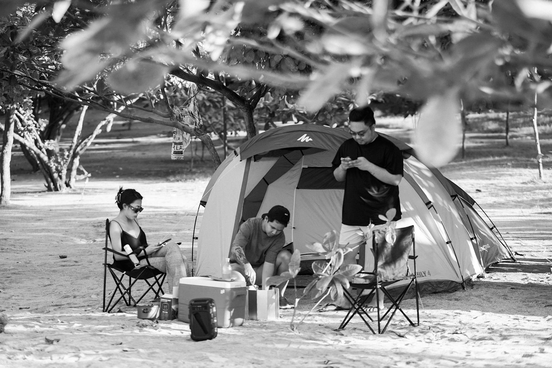 A group enjoying a camping trip with a tent set up in a sandy outdoor area.