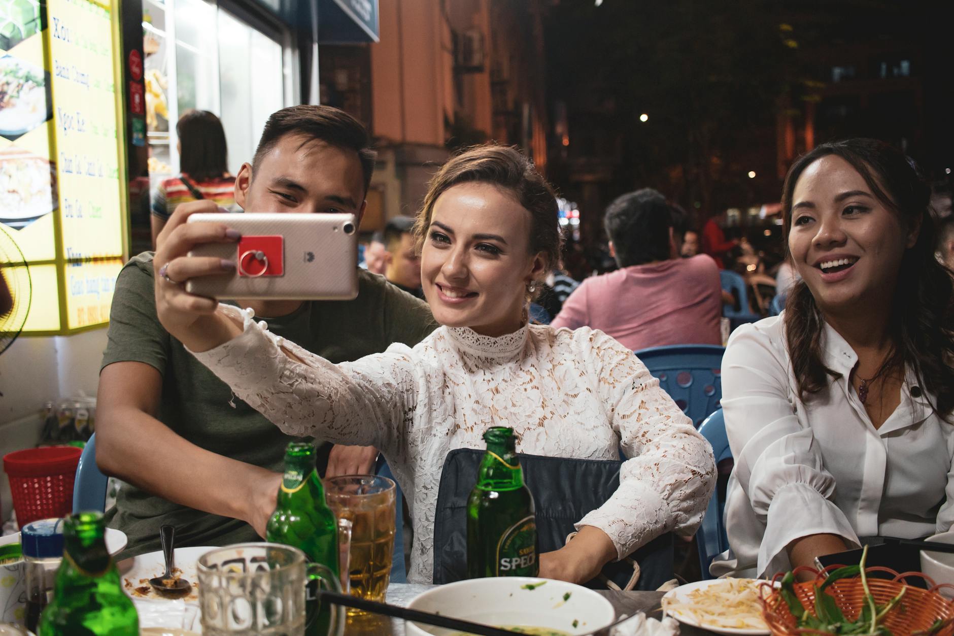Cheerful group taking a selfie at an outdoor restaurant, enjoying a lively evening.
