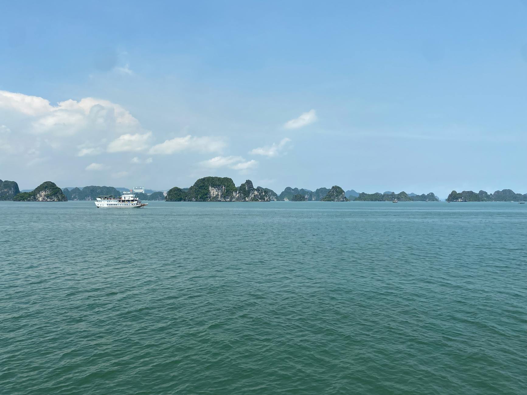 Breathtaking view of Ha Long Bay with islands and a boat under a clear blue sky.