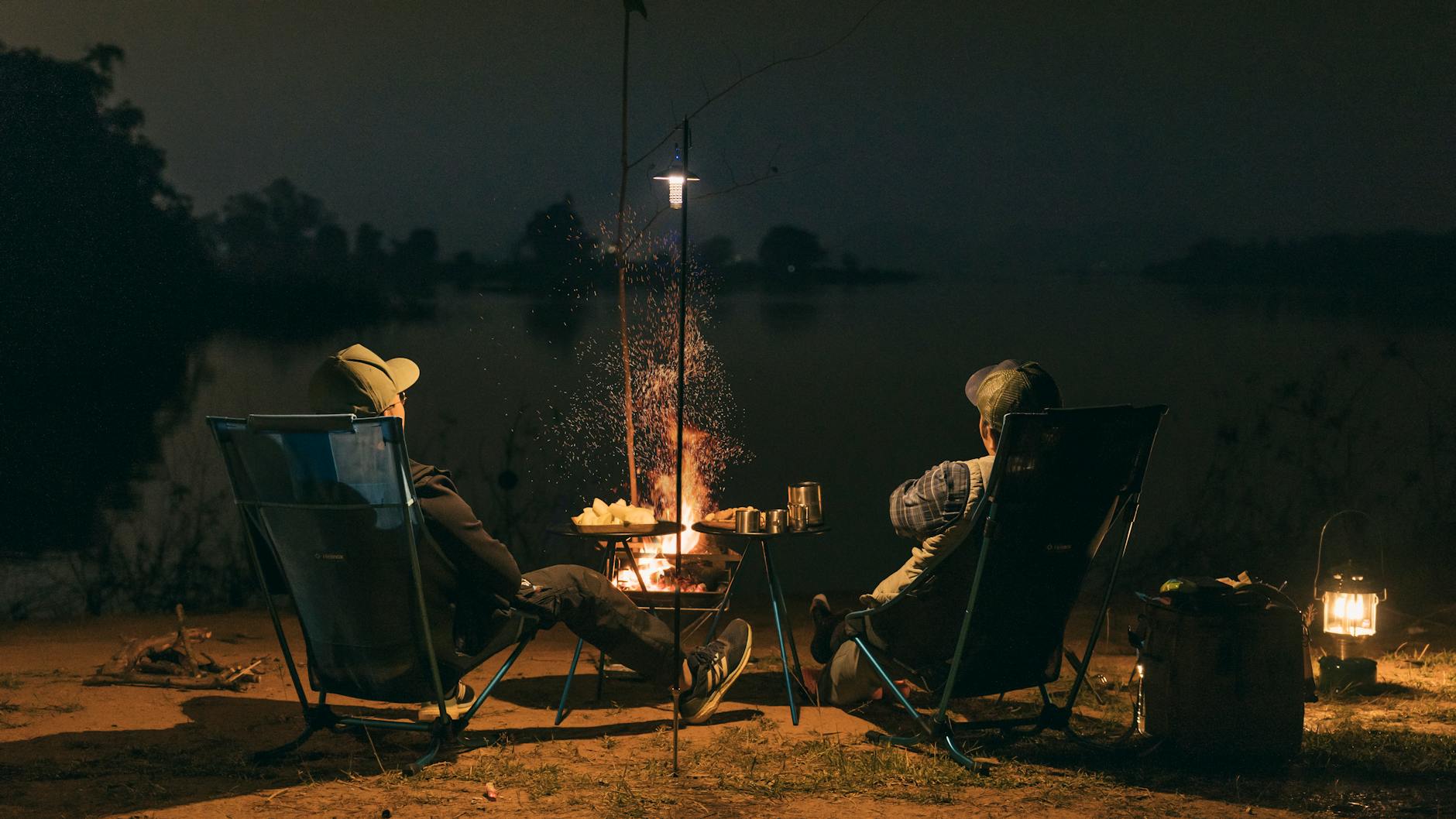 Two people enjoying a campfire by the lakeside at night in Sơn Tây, Vietnam.