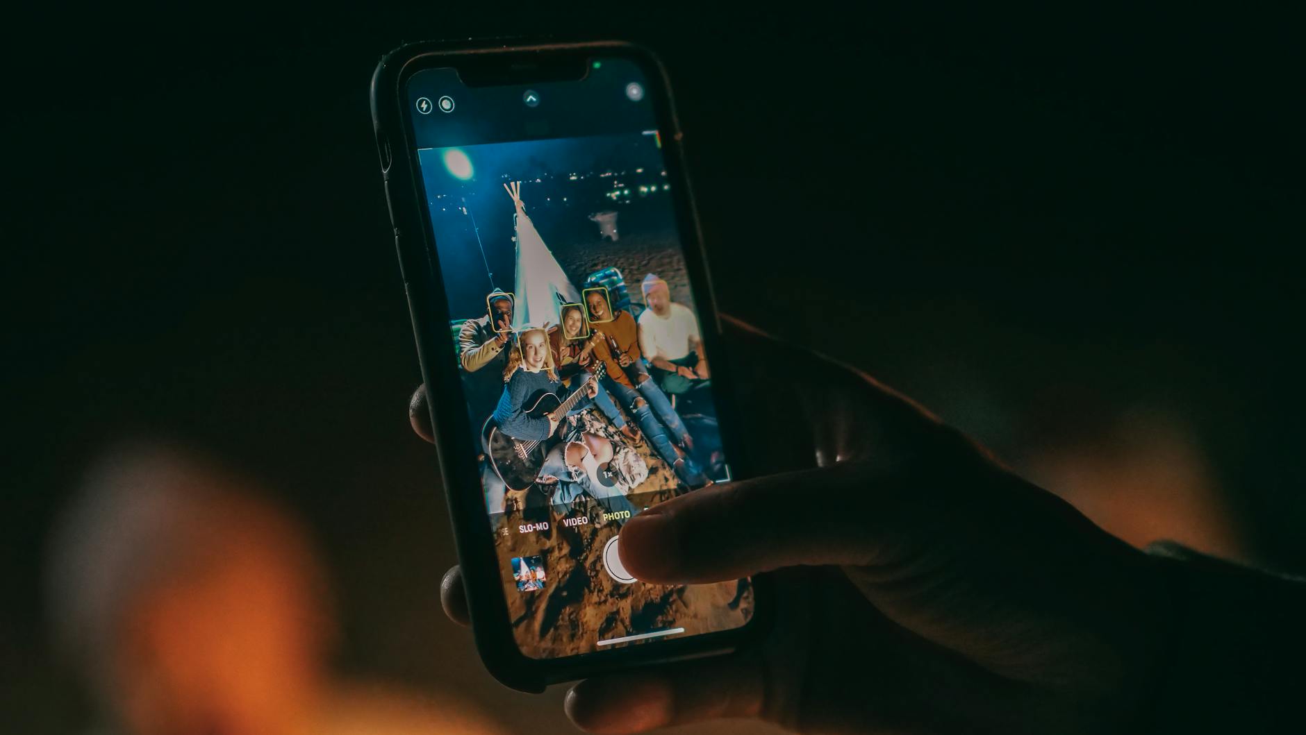 A group of friends enjoys a beach gathering, captured in a smartphone photo.