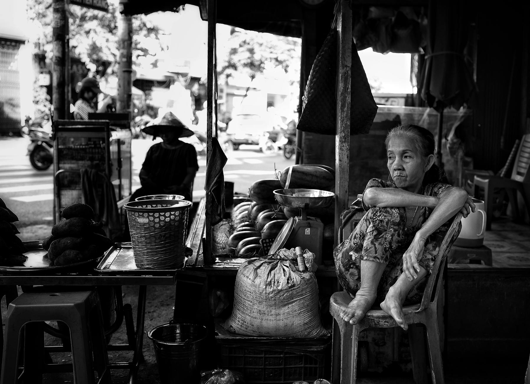 Black and white photo of an elderly woman at a market stall in Ho Chi Minh City, Vietnam.