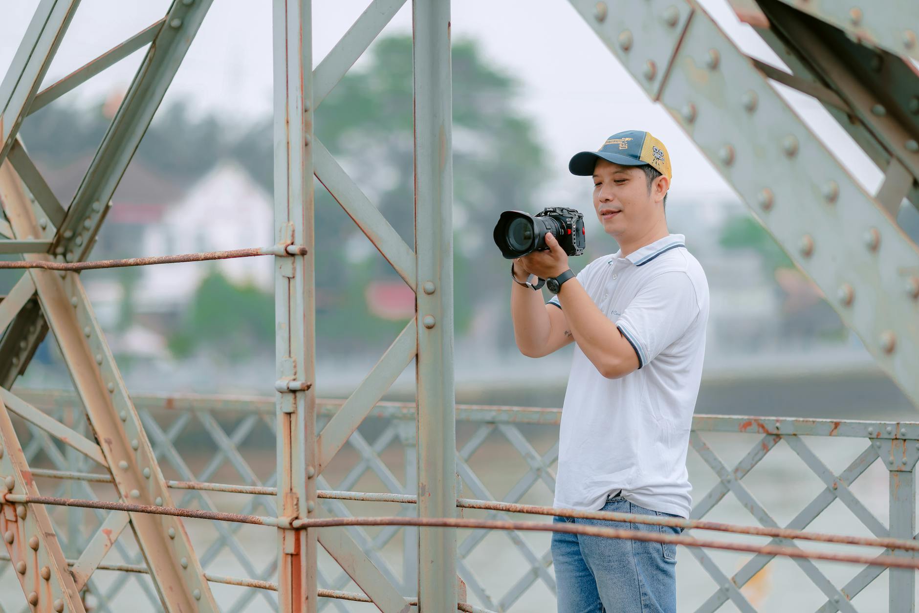 Man photographing scenic view from bridge with camera, outdoors.