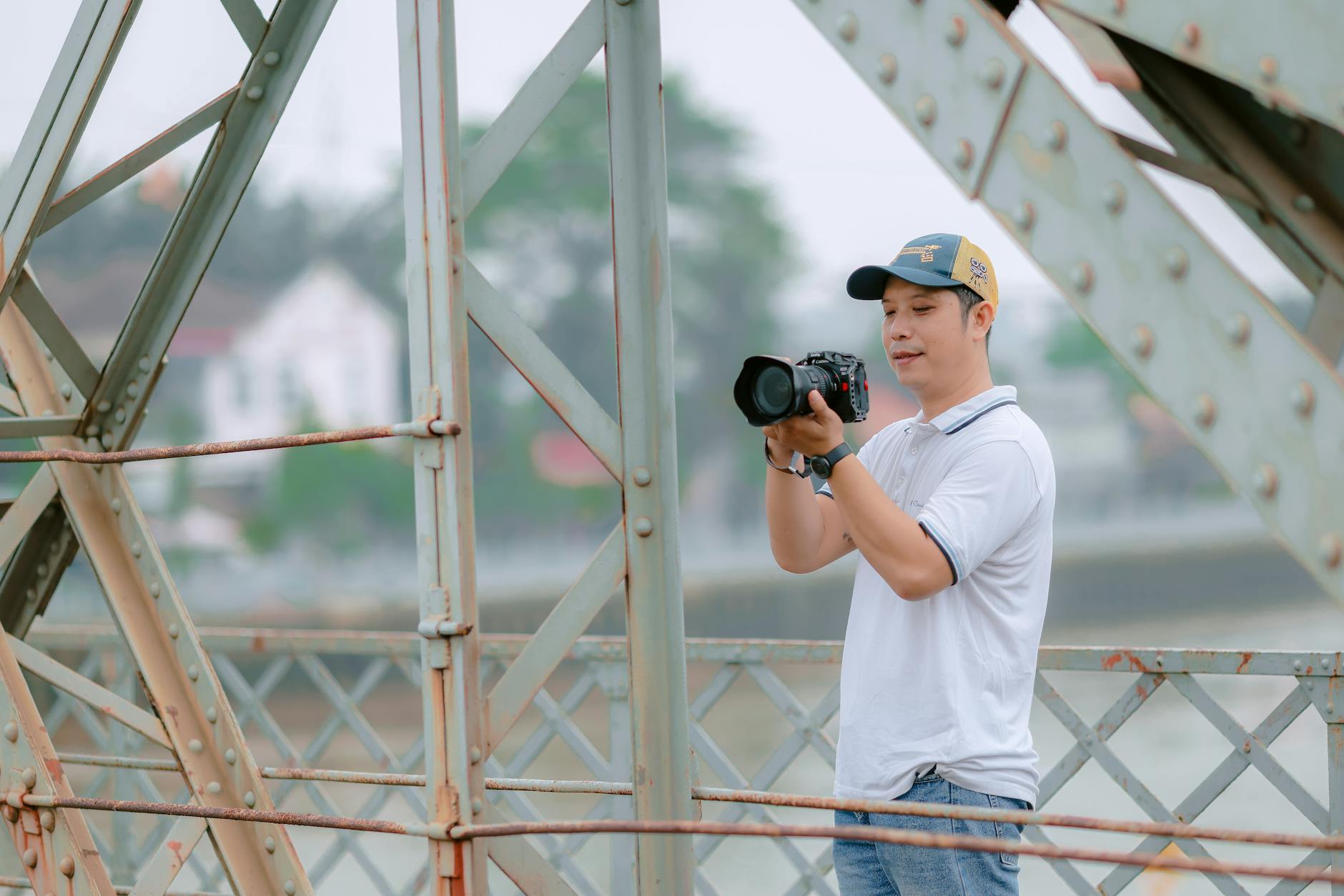 Man taking photos with a camera on an iron bridge outdoors.
