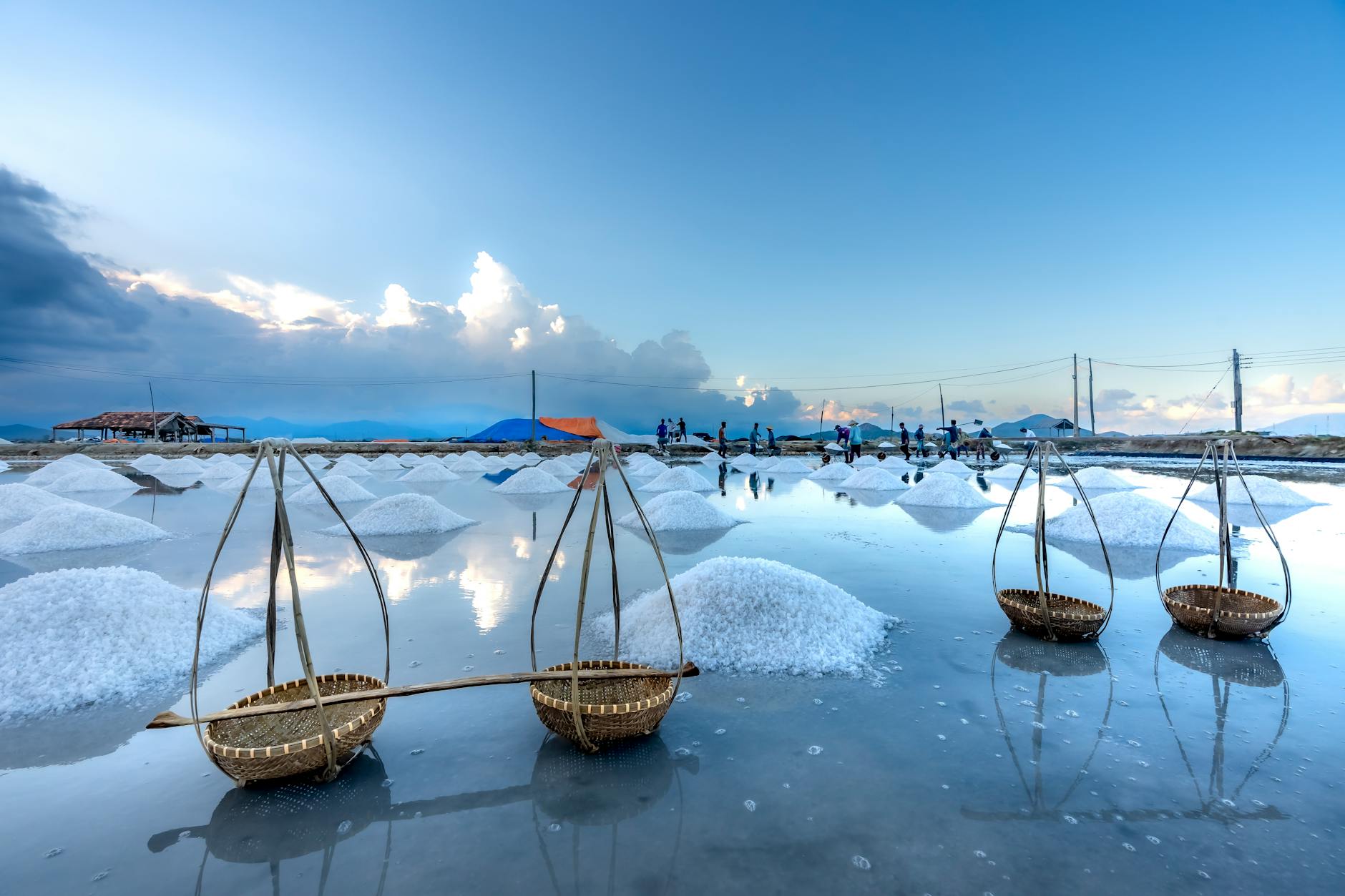 Salt flats reflecting the sky with traditional baskets, creating a serene, picturesque landscape.