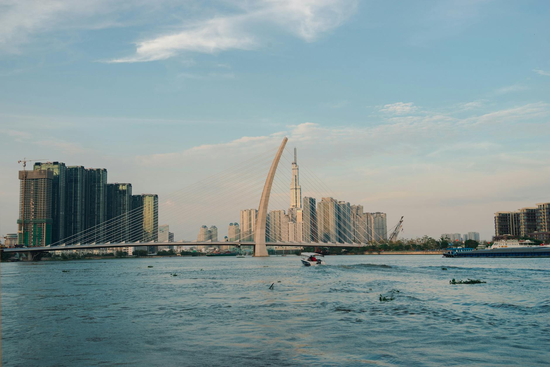 View of Ho Chi Minh City's skyline featuring Thu Thiem Bridge over Saigon River on a clear day.