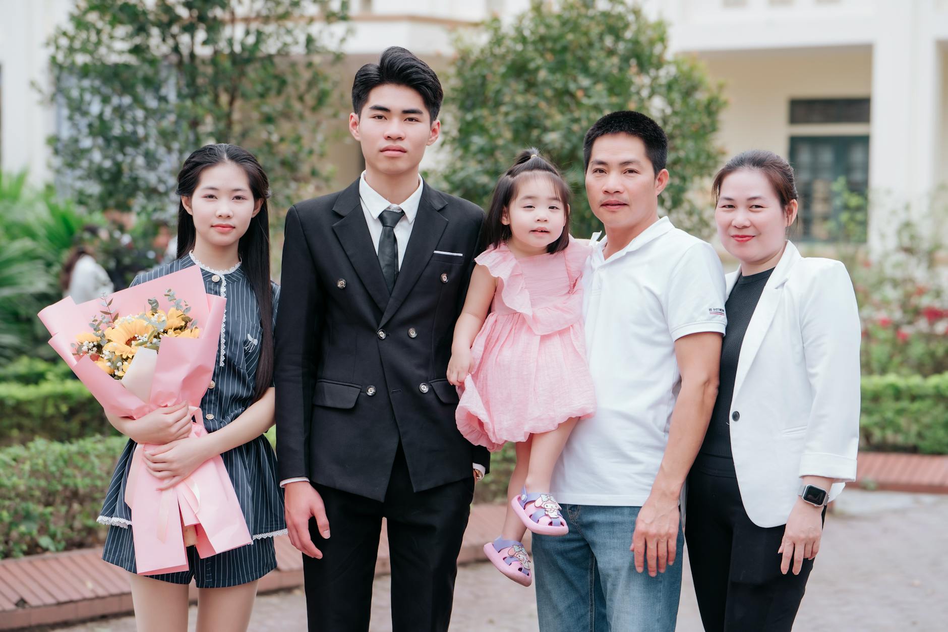 A smiling family of five posing outdoors during a celebratory occasion, capturing a joyous moment.