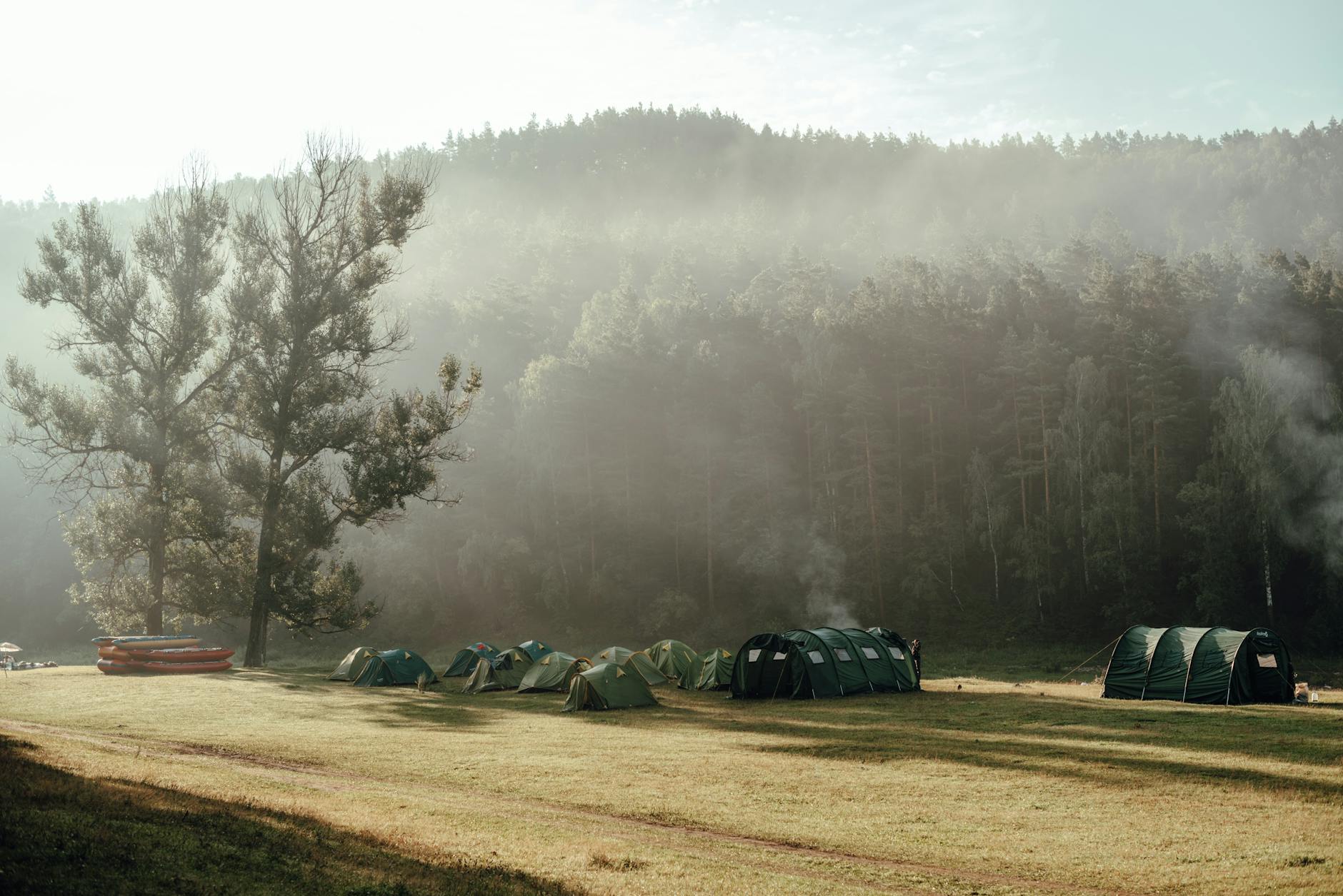 A serene campsite with tents in a misty forest clearing in Russia.