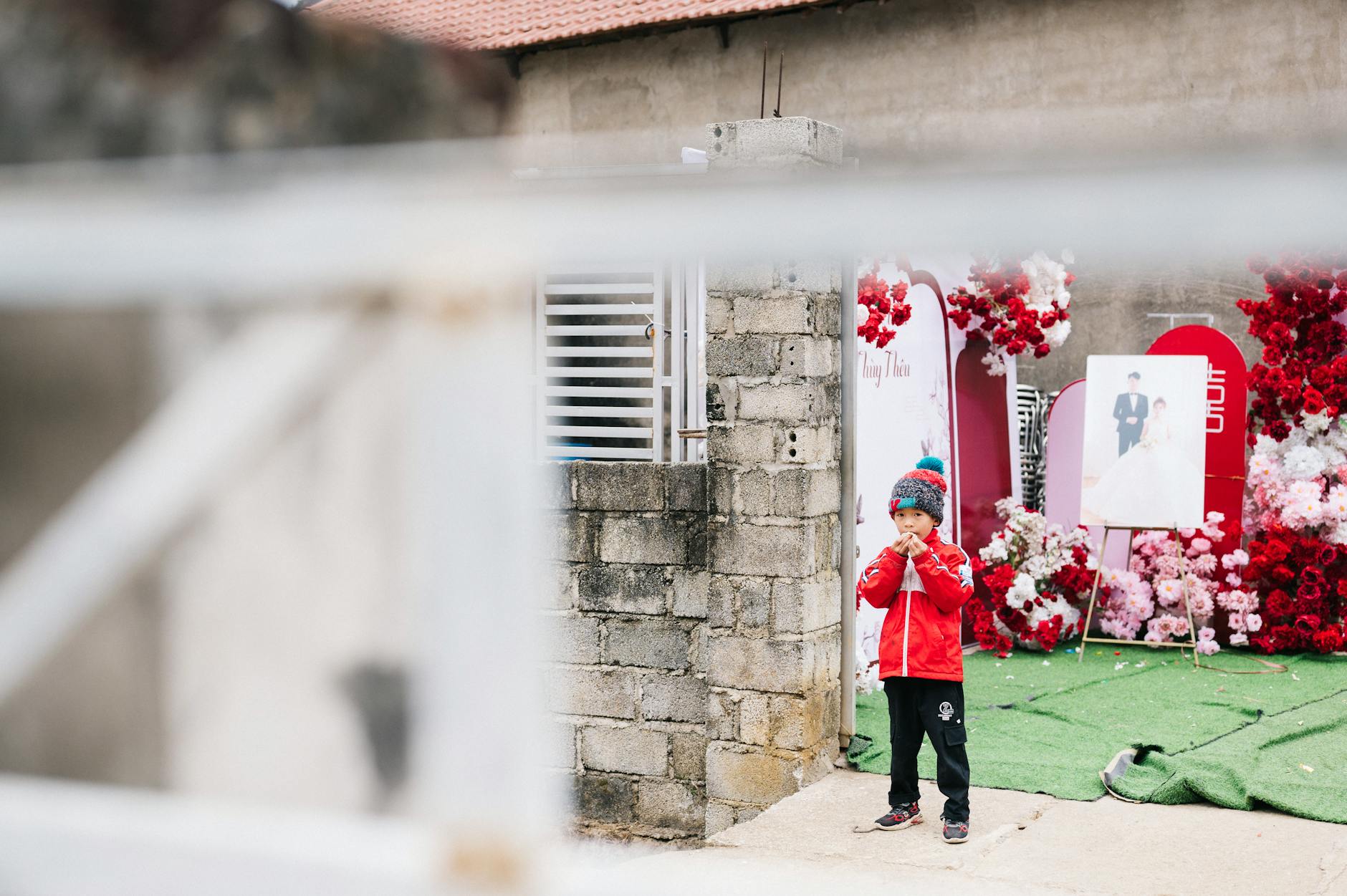 A young boy in colorful clothes near vibrant wedding decorations in Lạng Sơn, Vietnam.