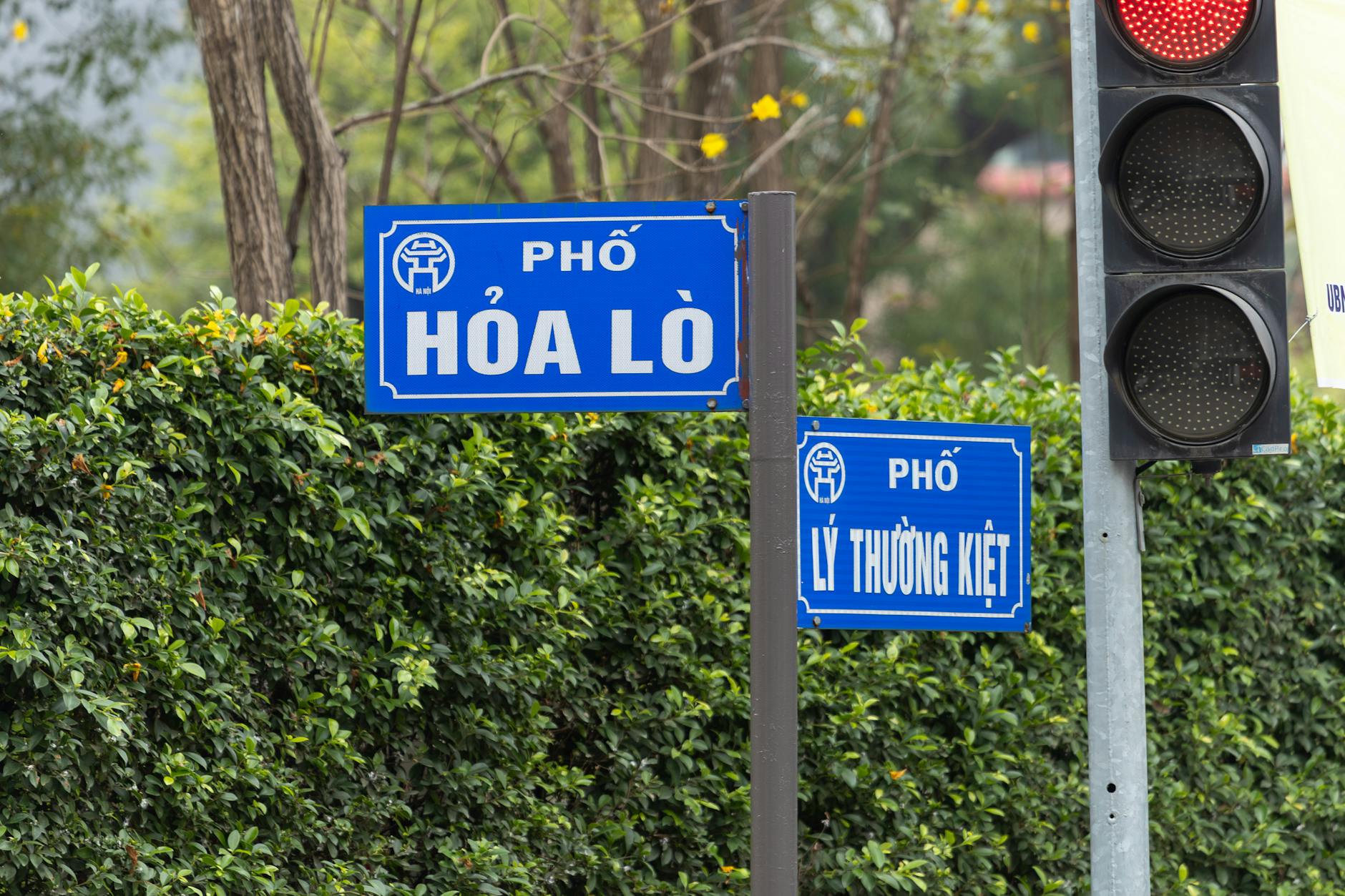 Street signs for Hòa Lò and Lý Thường Kiệt in Hanoi, Vietnam with traffic light.