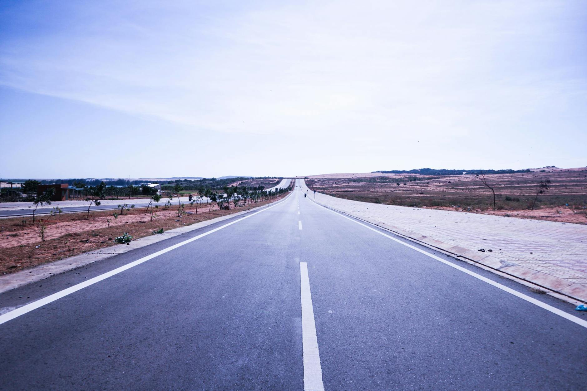 A straight, empty highway under a bright sky in Nha Trang, Vietnam, with distant views and clear road markings.