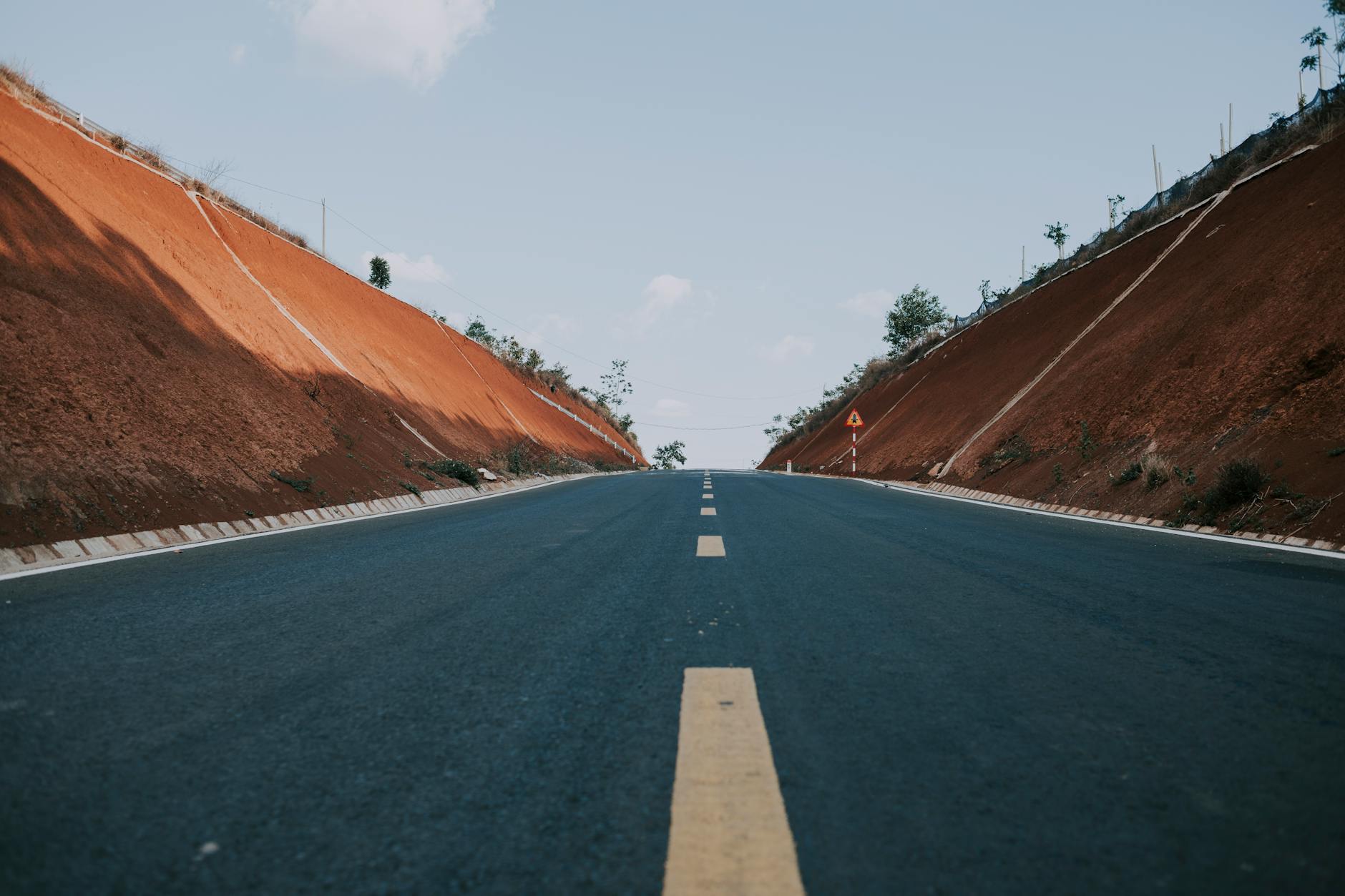 A wide highway cuts through desert hills under a clear blue sky, perfect for travel and exploration.