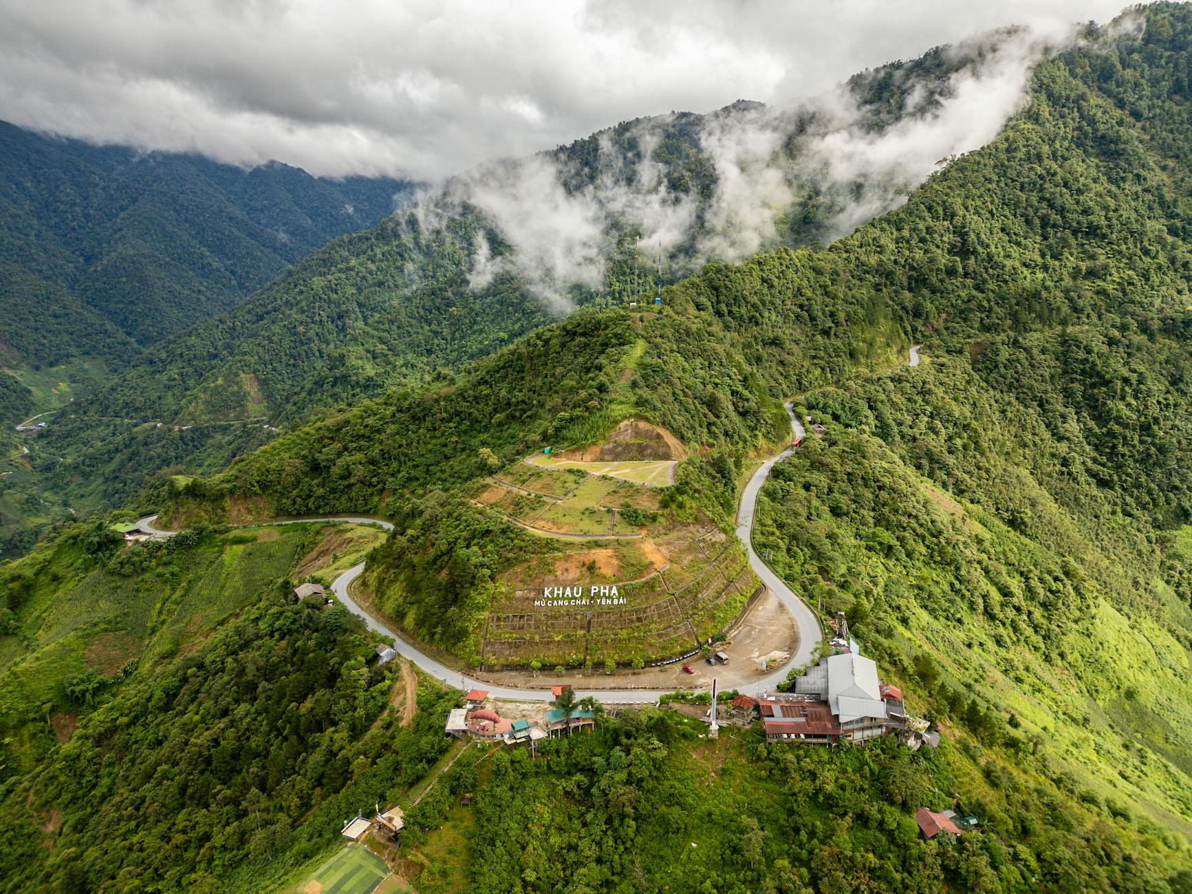 Stunning aerial view of Khau Pha Pass, a scenic mountain road in Mu Cang Chai, Vietnam, surrounded by lush greenery.