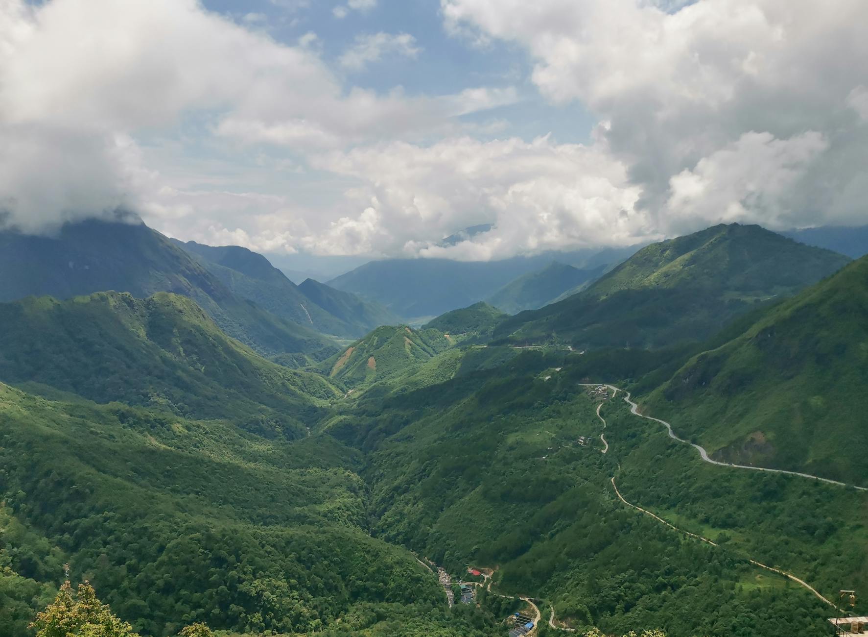Scenic aerial view of a lush green mountain valley under a cloudy sky.