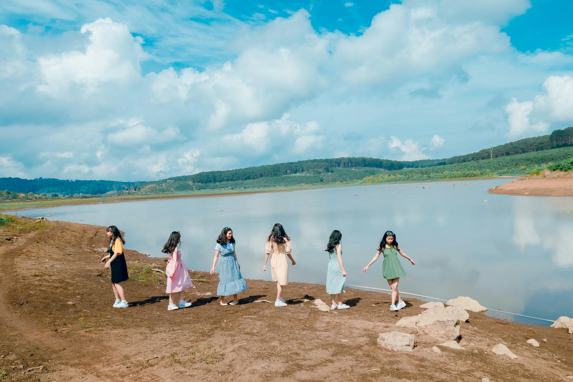 A group of young women enjoying a sunny day by the lake in a scenic landscape.