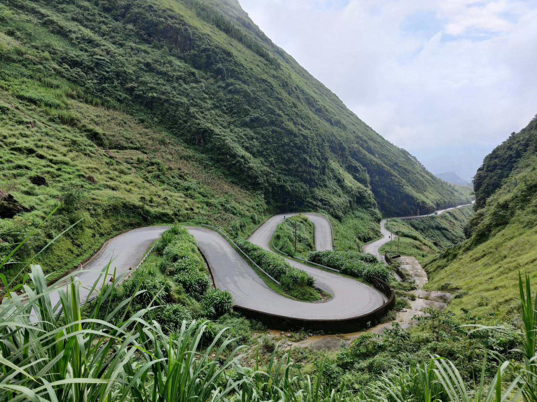 Scenic winding road in lush green mountains of Hà Giang, Vietnam.