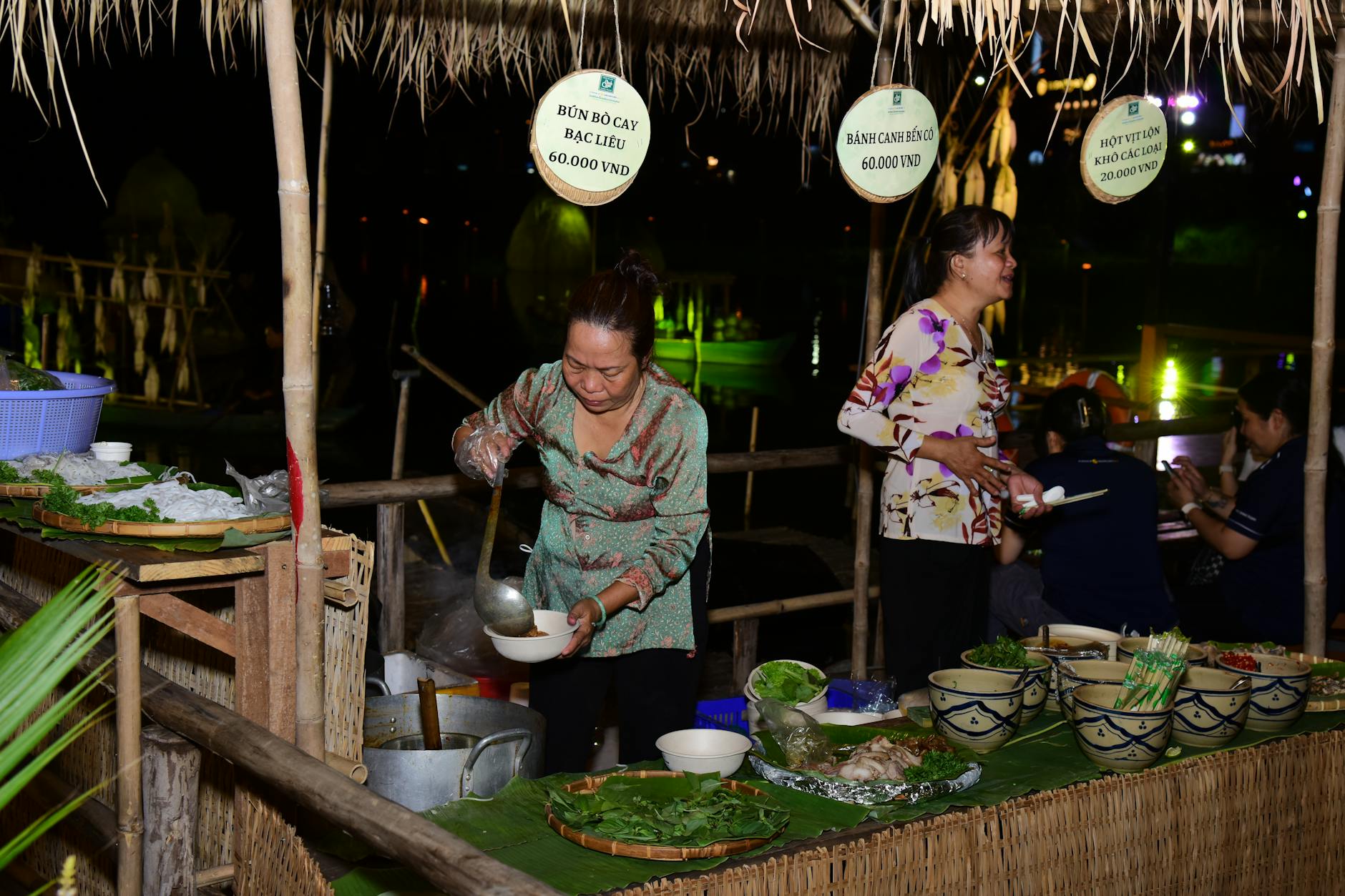 Vendor serving traditional Vietnamese dishes at a bustling night market.